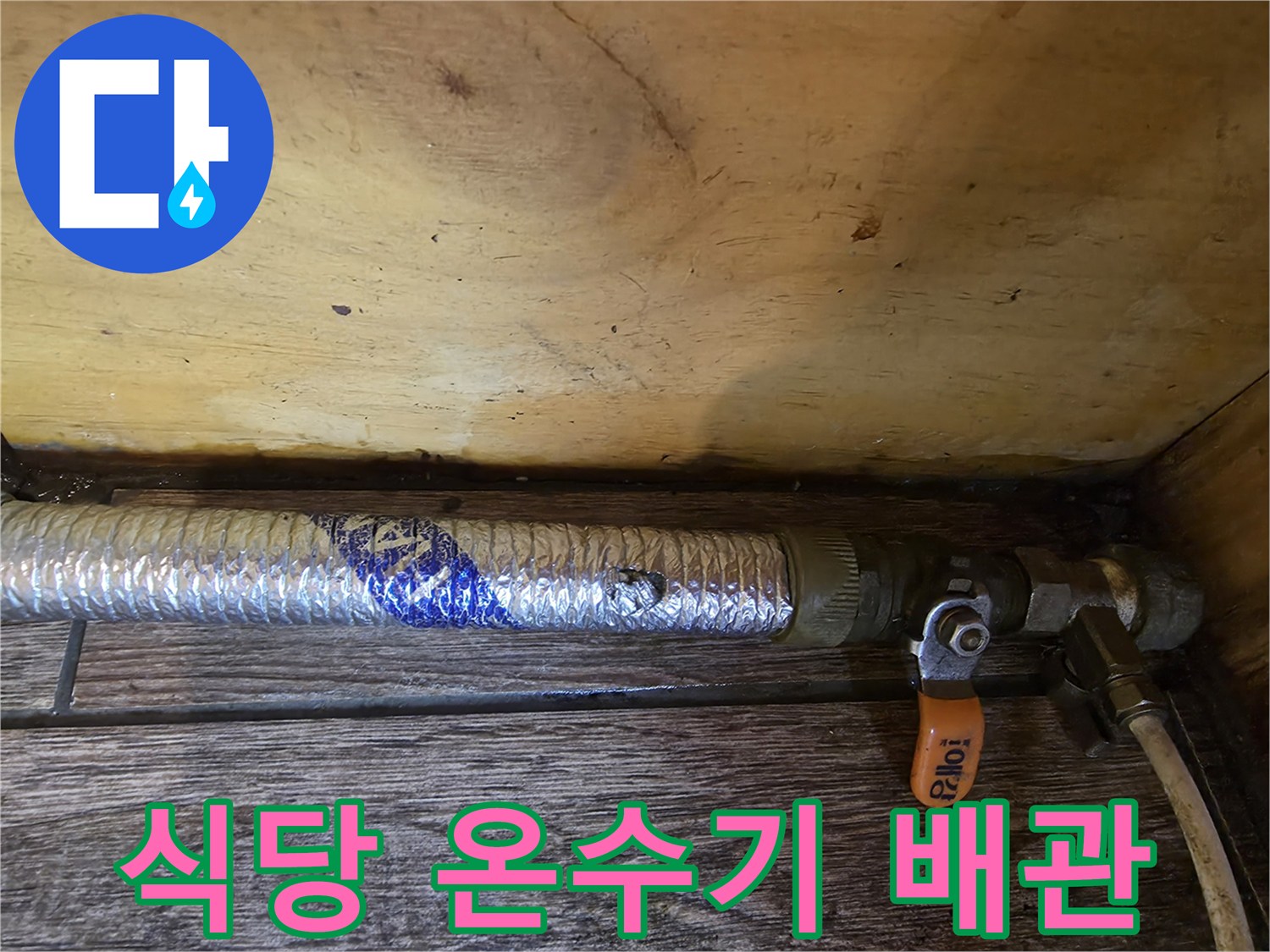 온수기 연결 배관과 주황색 밸브 핸들 상세