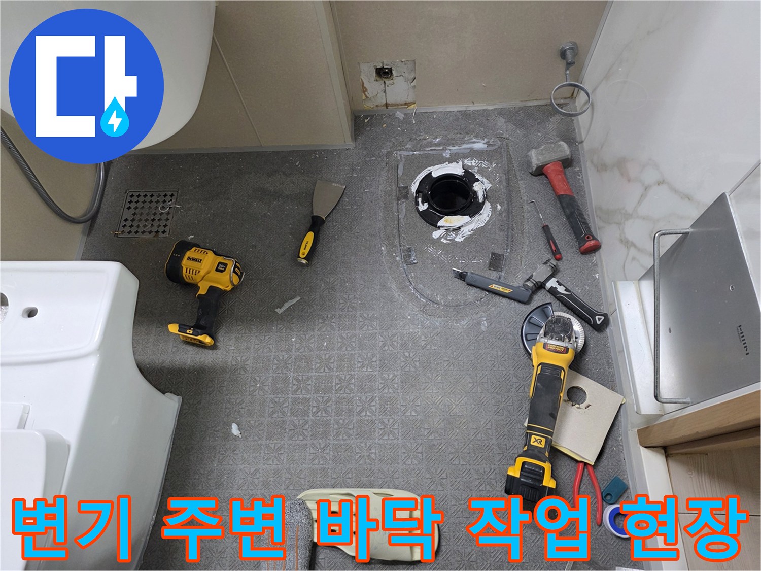화장실 변기 배관 수리를 위해 바닥 타일 일부를 제거하고 장비를 배치한 모습입니다.