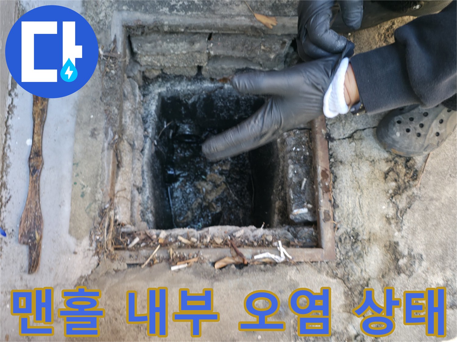 장갑을 낀 작업자가 맨홀 내부의 오물과 이물질 적체 상태를 확인하고 있습니다.