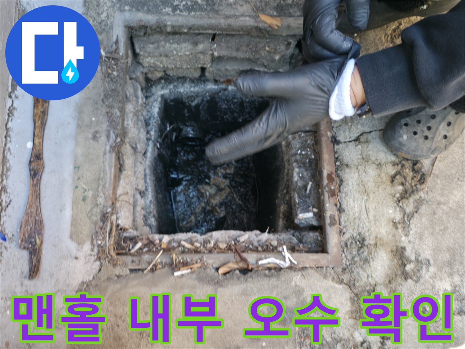 장갑을 낀 작업자가 맨홀 안쪽의 막힌 배관 상태를 조사하는 모습