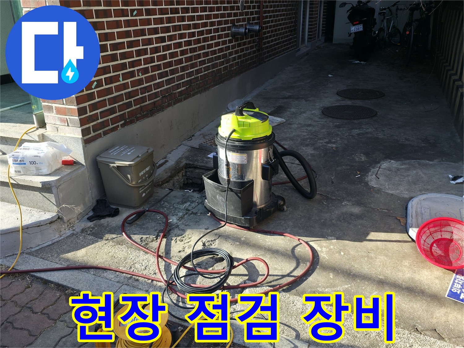 하수 역류 현장에 배치된 산업용 청소기와 배관 점검 장비입니다.