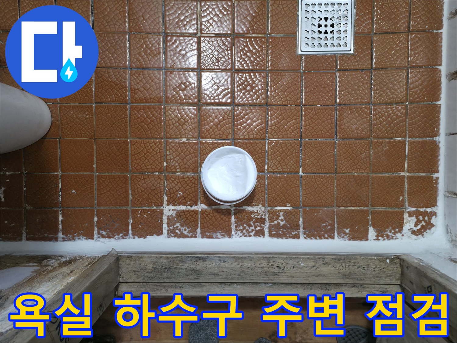 갈색 타일 벽면의 배수구와 파이프 연결 부위