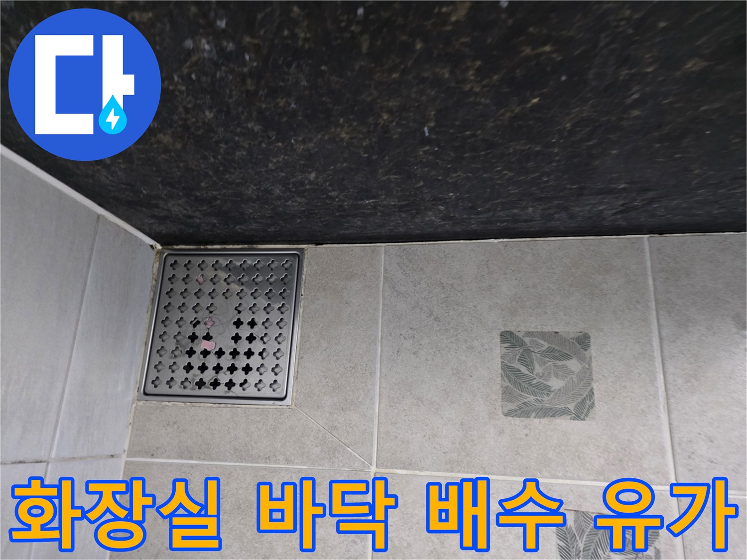 패턴 타일과 하수구 유가가 맞닿은 부위의 근접 촬영 사진입니다.