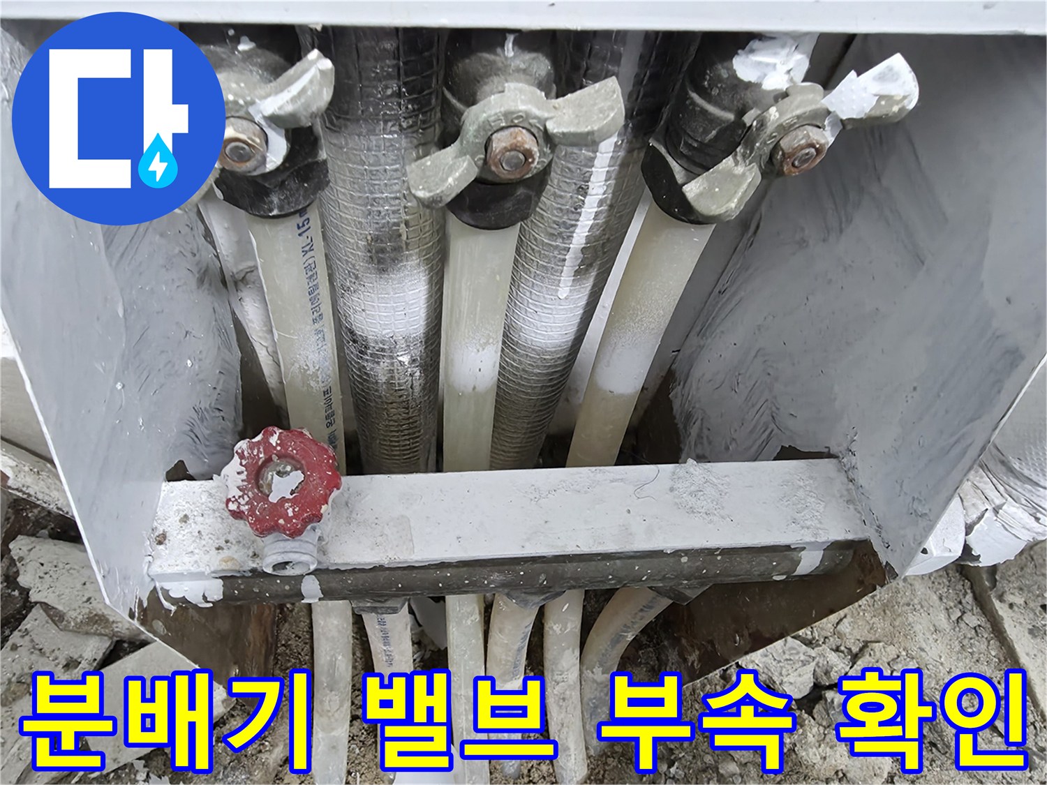 노후된 분배기 밸브와 하얀색 난방 배관의 연결 구조를 보여주는 사진입니다.
