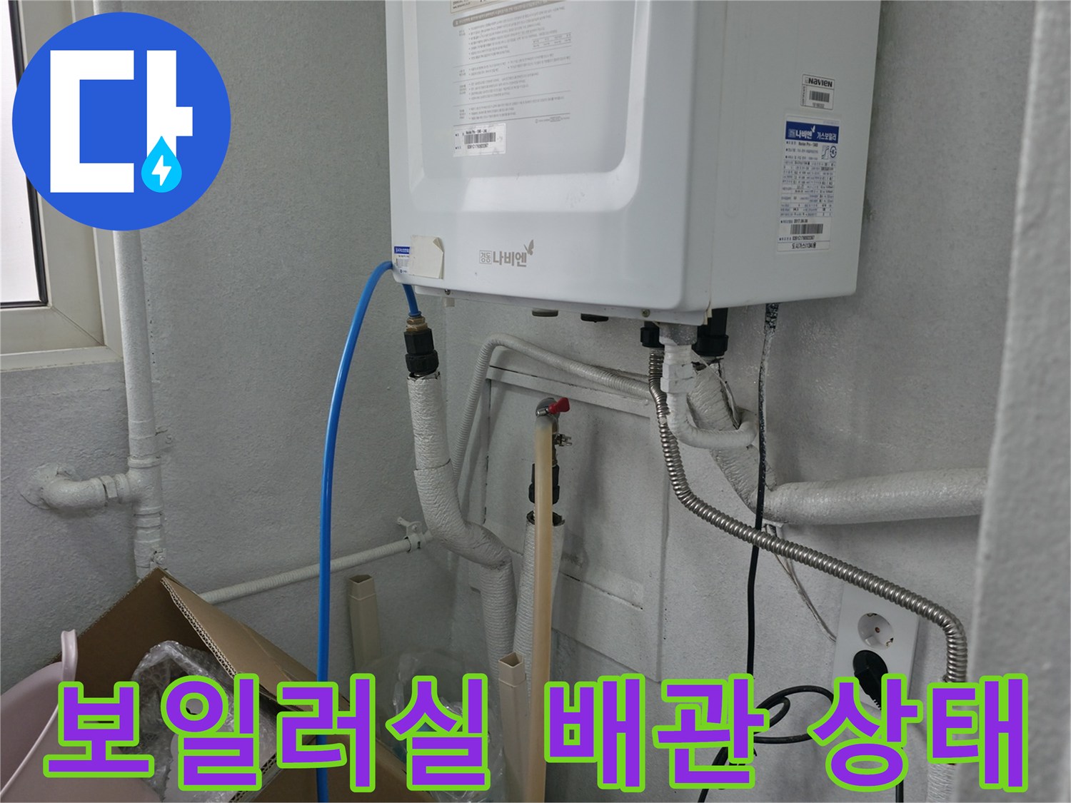 보일러 하단에 연결된 다양한 배관과 전기 콘센트 모습