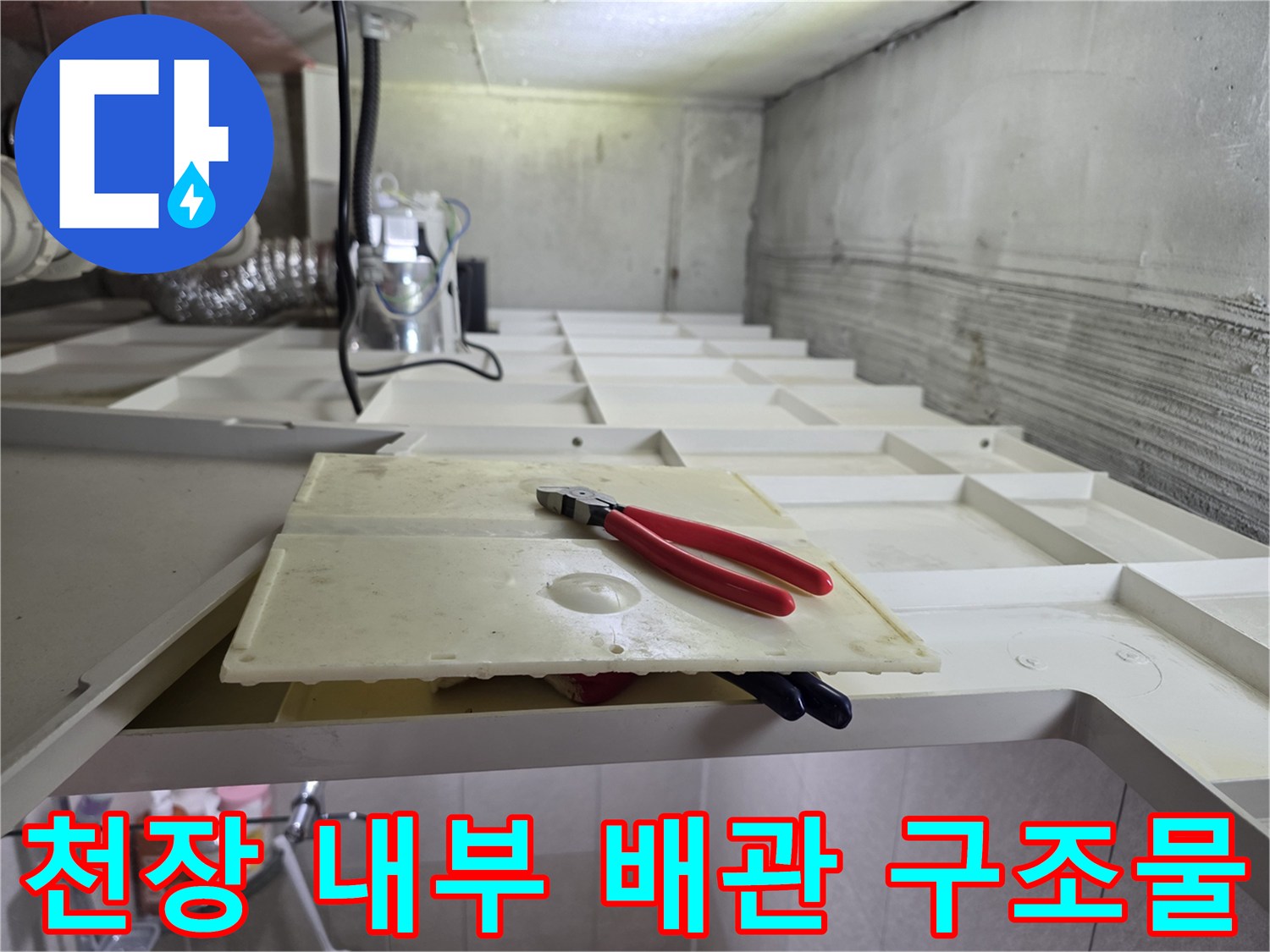 화장실 천장 안쪽의 배관들과 작업용 펜치 사진입니다.