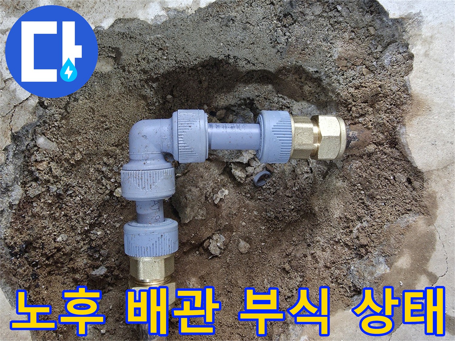 흙과 콘크리트 사이로 드러난 부식된 금속 배관 연결부