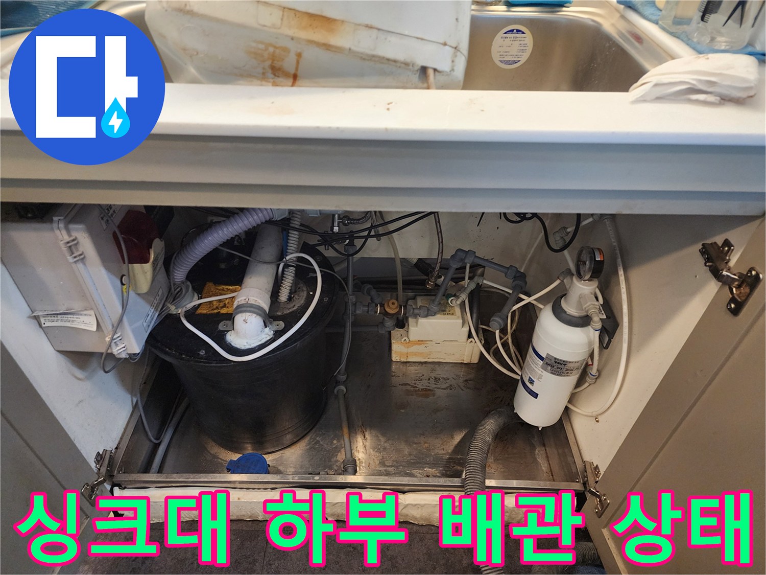 서초구 상업 공간 싱크대 하단부의 복잡한 배관과 물기가 고인 바닥 모습