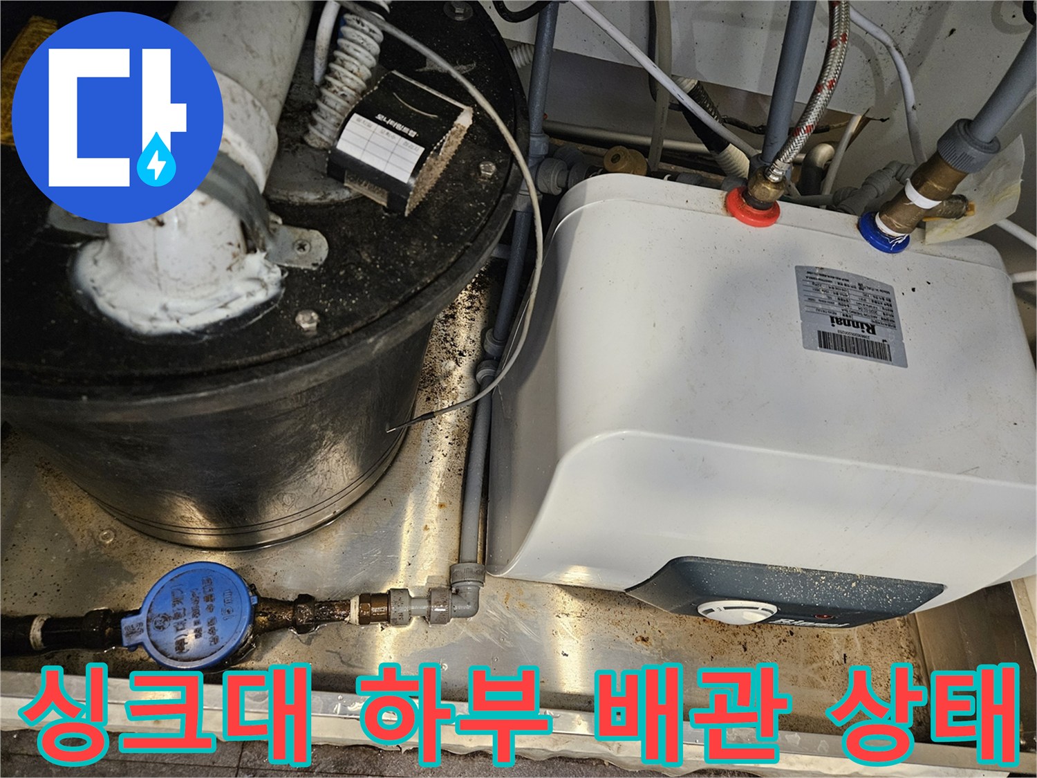싱크대 아래 온수기와 연결된 배관들의 복잡한 구조를 보여줍니다.