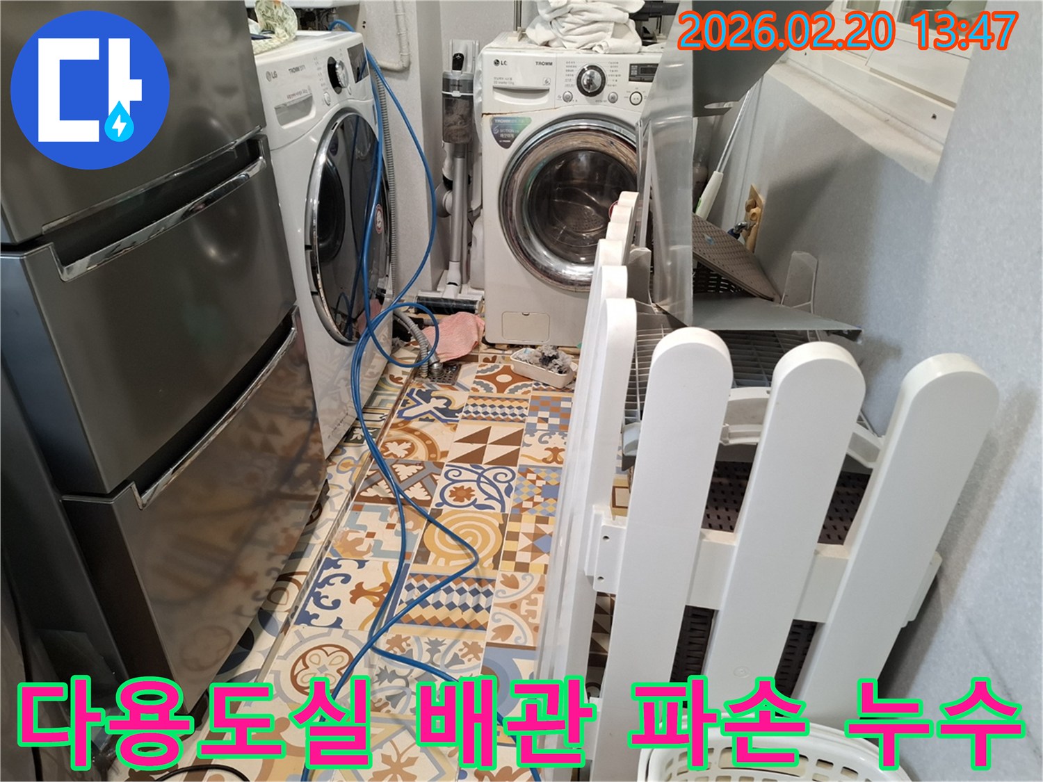 주택 다용도실 바닥에 누수 탐지 장비 호스가 설치되어 있고-배관 파손으로 인한 누수를 긴급 복구하는 현장입니다.