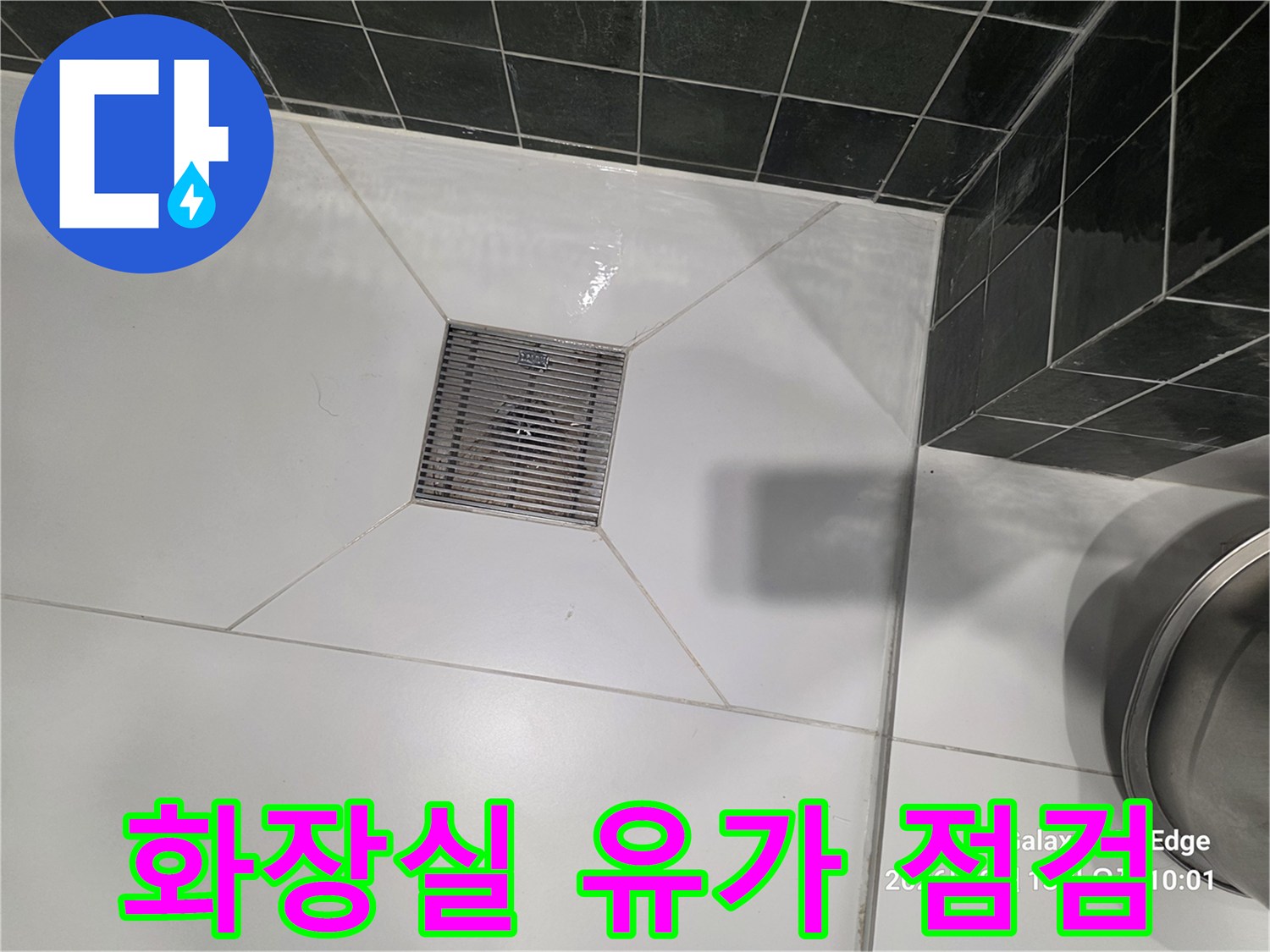 깨끗한 흰색 타일과-중앙의 금속제 배수구 덮개 모습입니다.