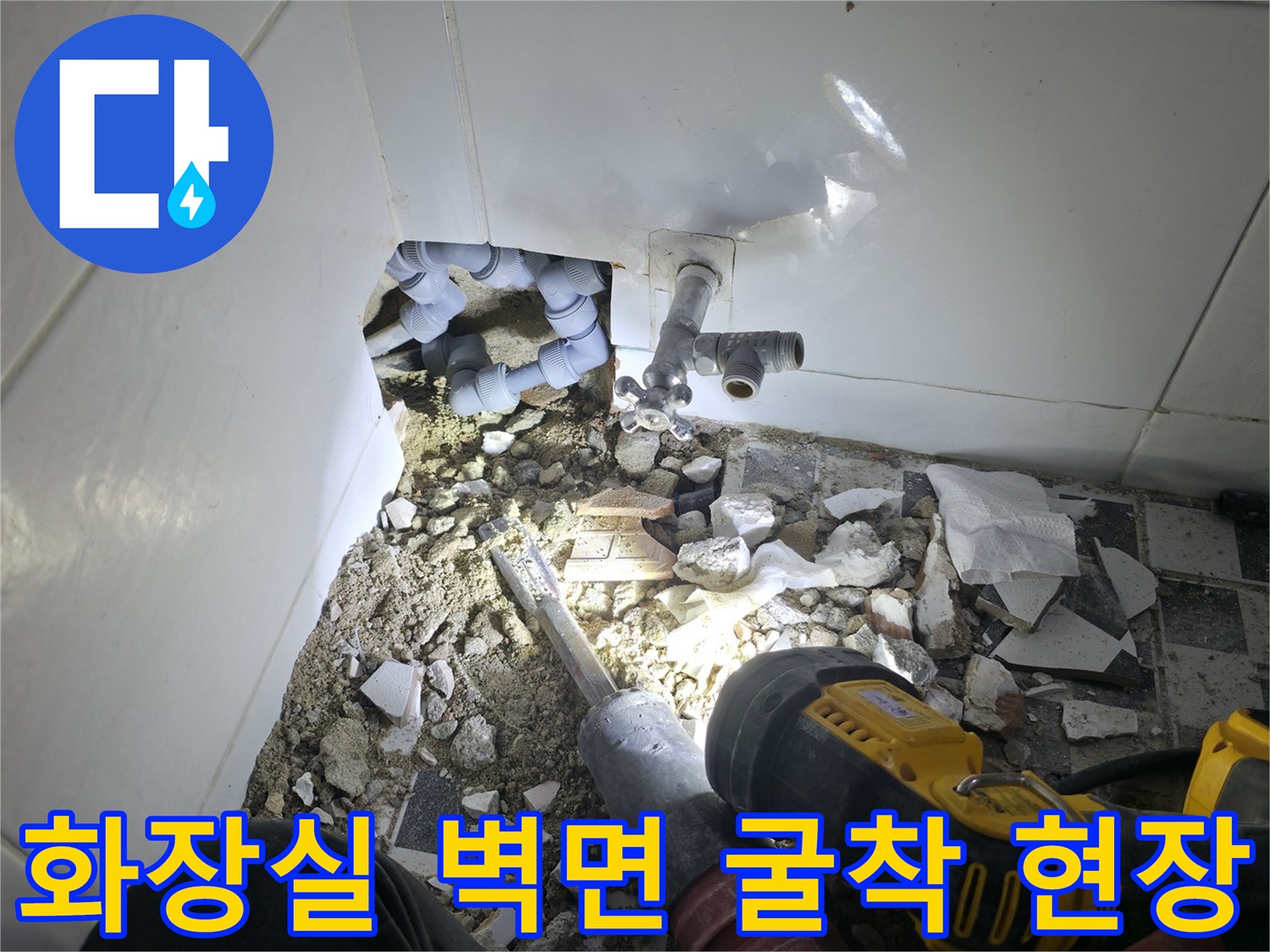 깨진 타일과 파편들 사이로 노출된 은색 수도 연결 부속