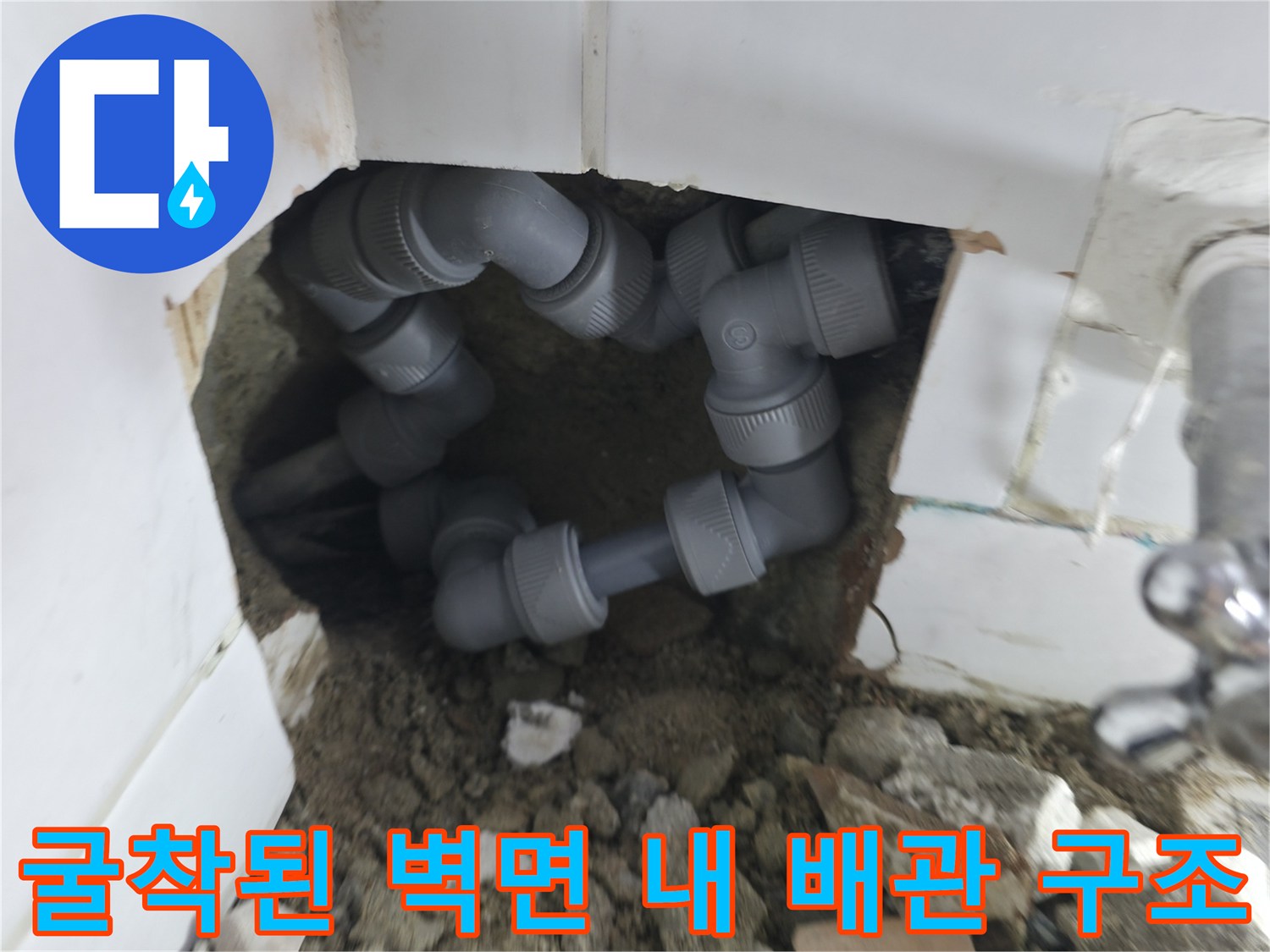벽면 타일 제거 후 드러난 회색 배관과 연결 부위의 모습