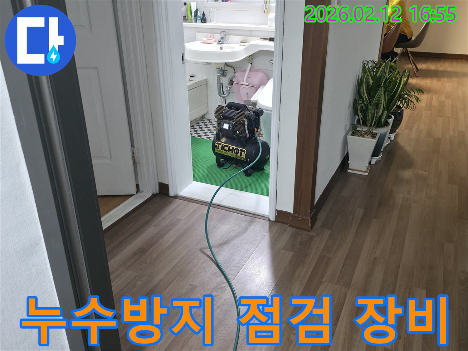 욕실 문턱에-놓인 누수-탐지용 압력-장비에서-녹색 호스가-연결되어-누수방지를-위한-정밀 점검-준비 과정
