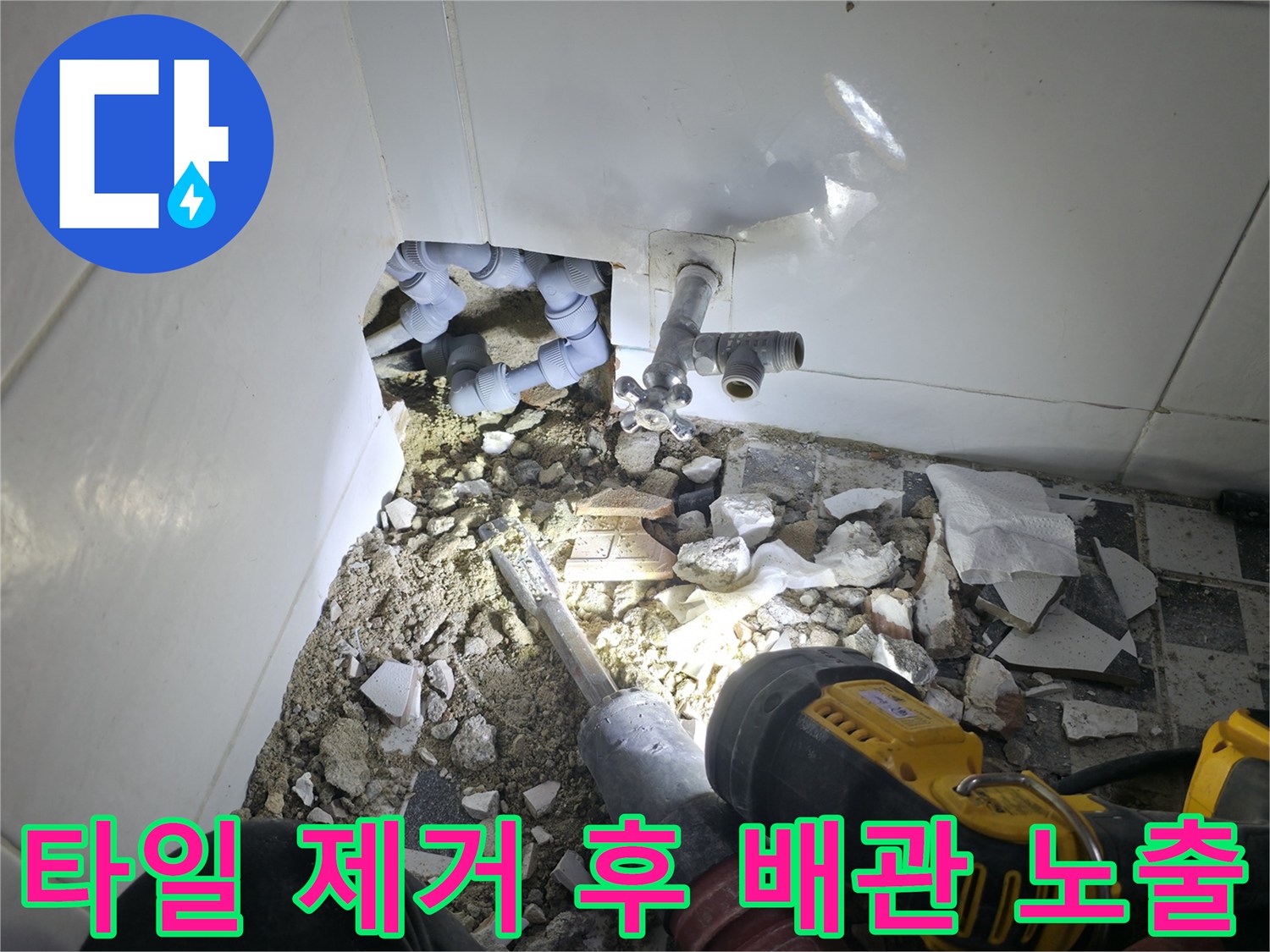 파쇄된 타일 조각들 사이로 보이는 수도 연결 부위와 장비