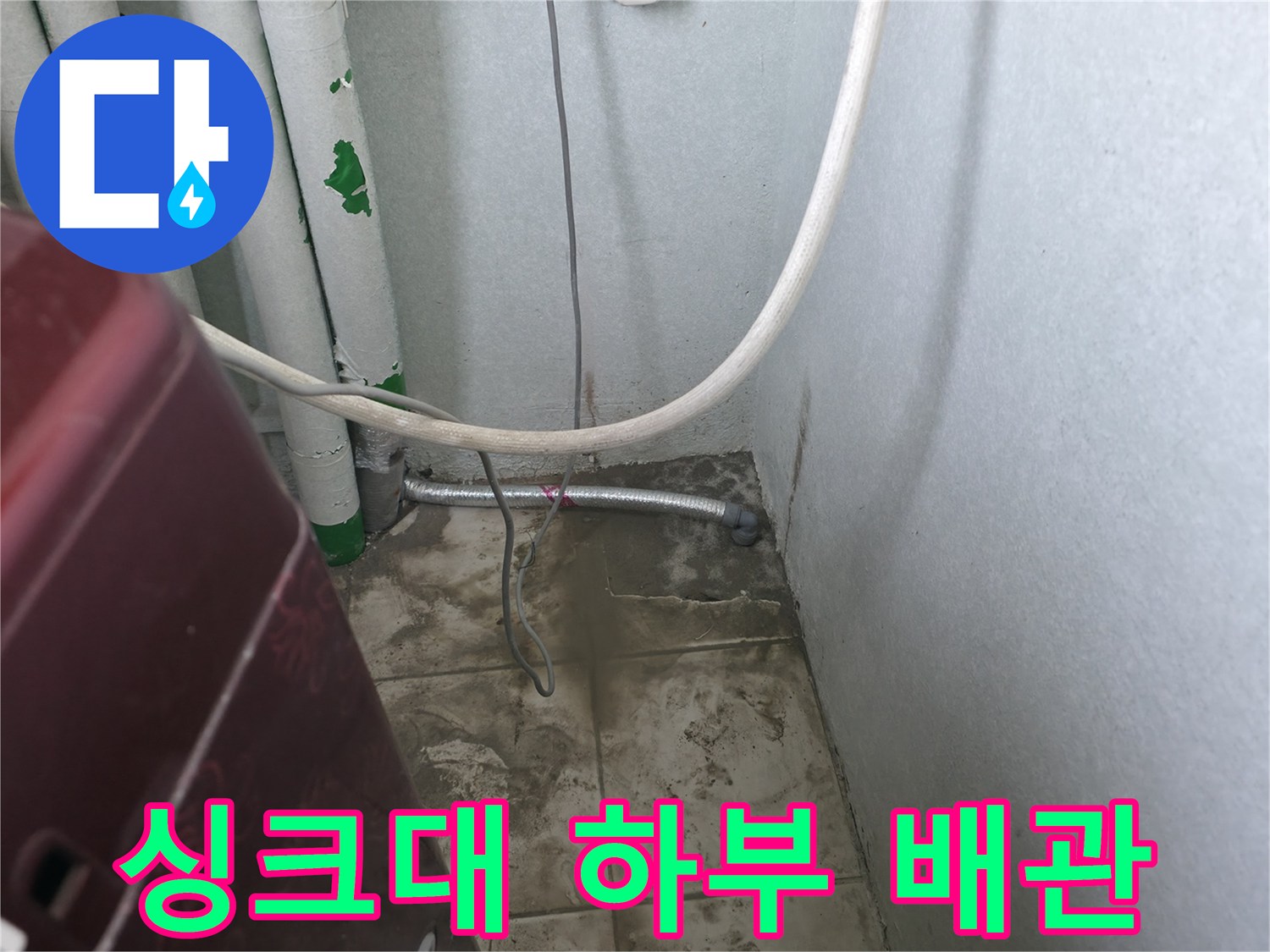 주방 싱크대 아래쪽의 흰색 배관과 금속 관 연결 부위
