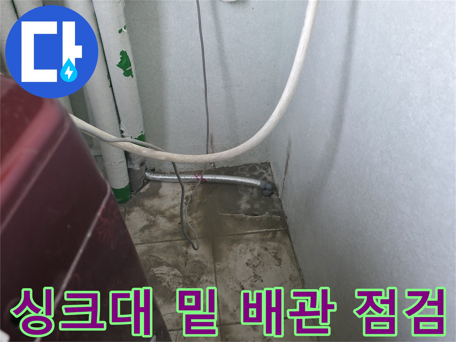 주방 싱크대 하단에 노출된 흰색 배관과 금속 관 연결 부위 상세