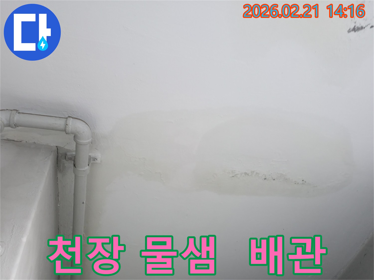 천장에서 물이 새어 얼룩진 모습과-그 옆으로 지나가는 배관이 함께 보이는 사진