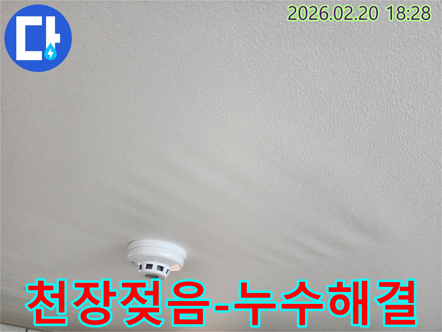 천장이 물에 젖어 변형된 모습으로 누수 문제가 심각함을 보여줍니다-화재경보기 주변의 손상이 우려됩니다