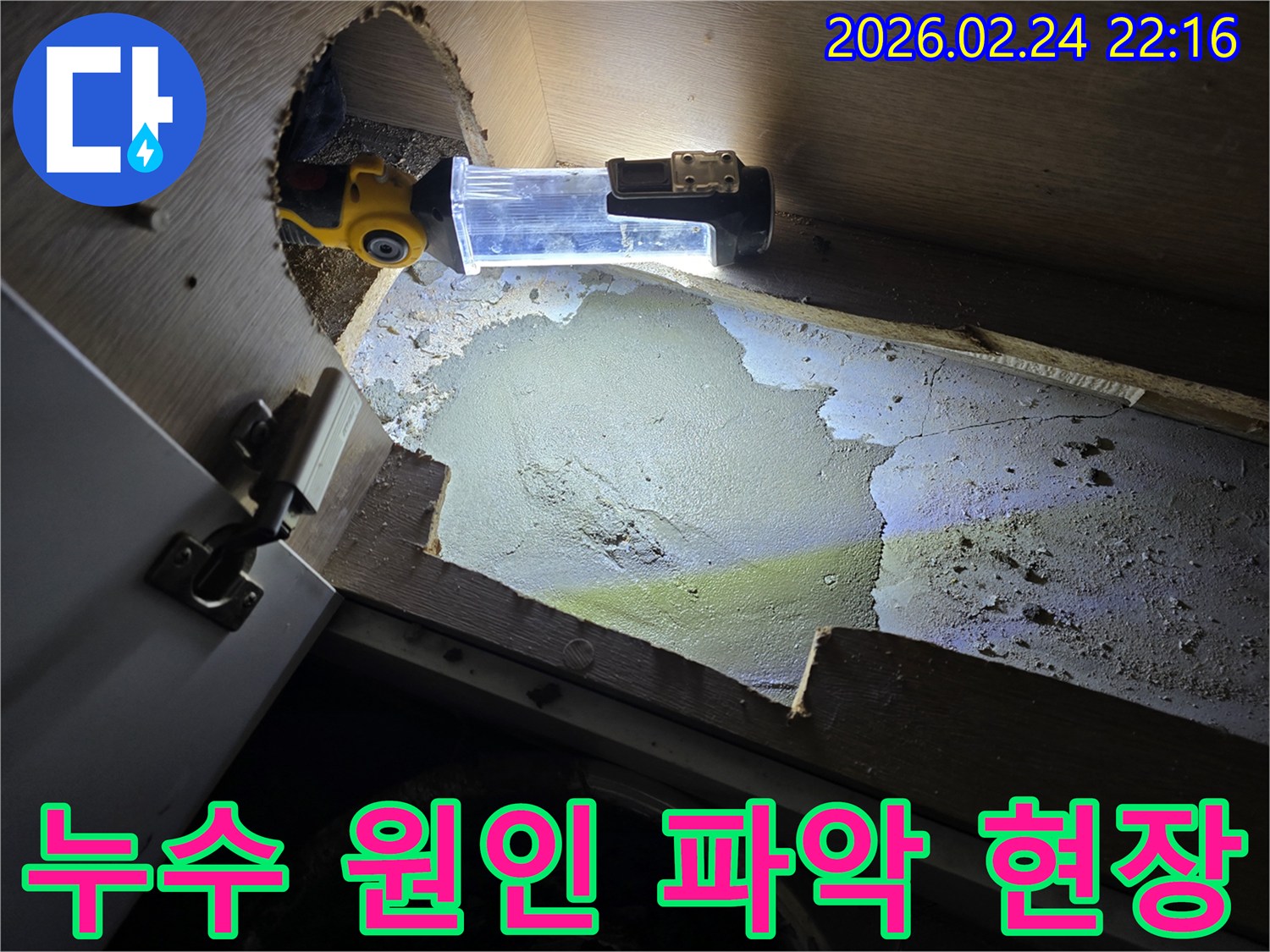 누수-전문가가-어두운-싱크대-하부에서-누수-원인을-파악하기-위해-조명-장비를-사용하여-정밀-조사하는-모습