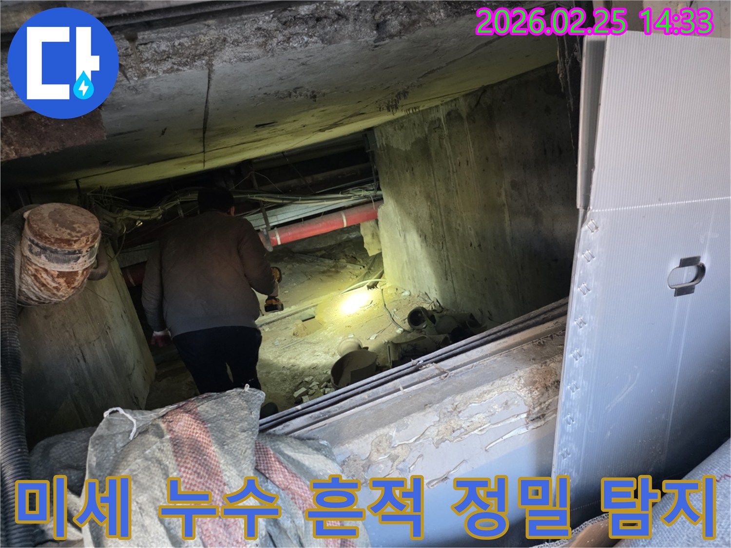 누수 전문 엔지니어가-어둡고 좁은 공간에서-손전등을 비춰가며-배관의 미세한 누수 흔적까지-놓치지 않고 탐지하는 모습입니다.