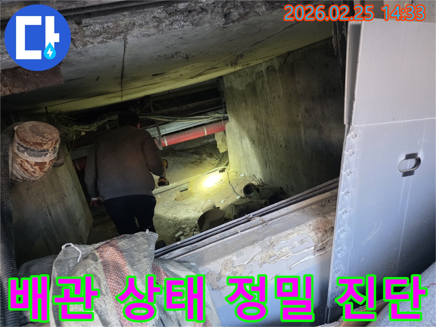 누수 전문 엔지니어가-어둡고 좁은 공간에서-손전등을 비춰가며-배관의 미세한 문제까지-전문가의 노하우로-세심하게 진단하는 모습입니다.
