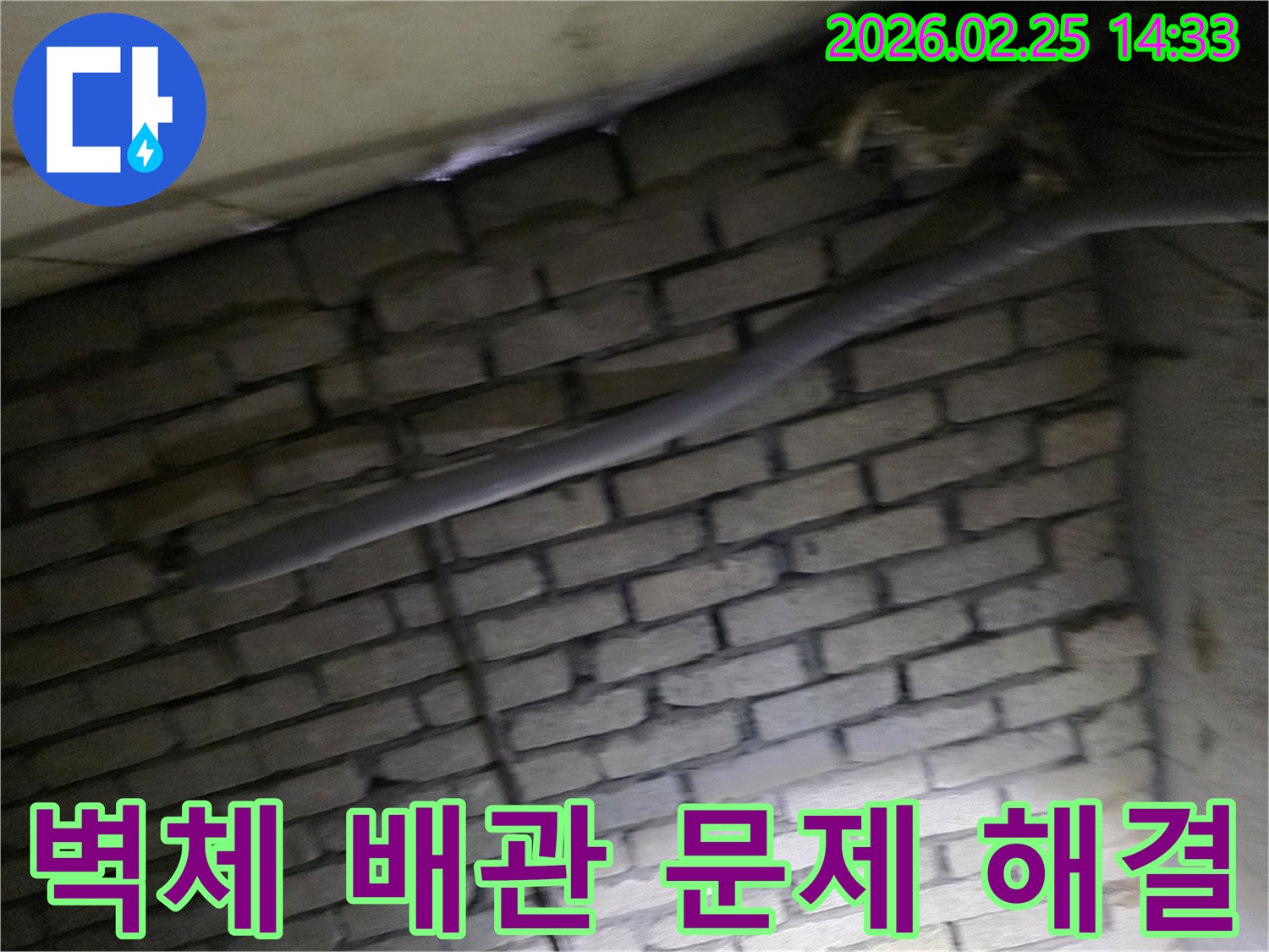 어두운 벽돌 벽면을 배경으로-단열된 배관과 전기 배선이-누수 여부를 확인하기 위해-정밀하게 검사되는 모습입니다.