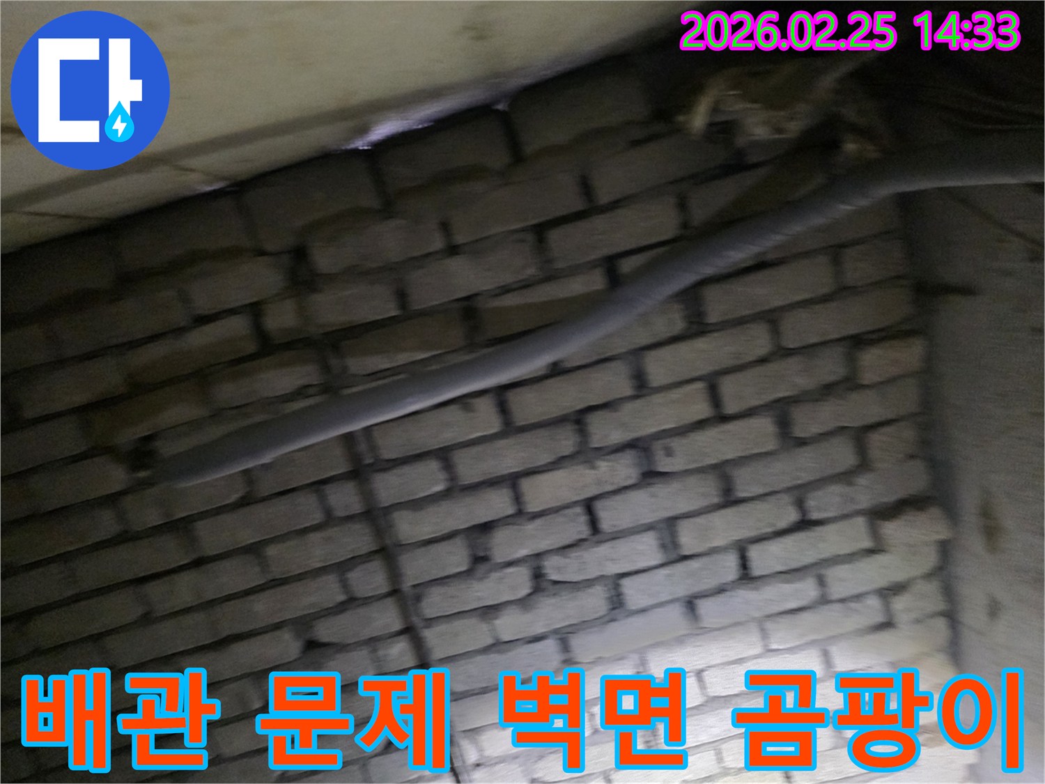 어두운 벽돌 벽면을 배경으로-단열된 배관과 함께-누수로 인한 벽면 곰팡이를-제거하기 위해 검사되는 현장 모습입니다.