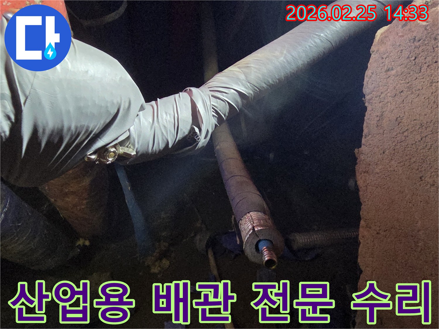 어두운 작업 공간에서-장갑을 낀 손이-두꺼운 산업용 배관의-손상된 연결 부위를-세심하게 점검하며-수리 작업을-준비하는 모습입니다
