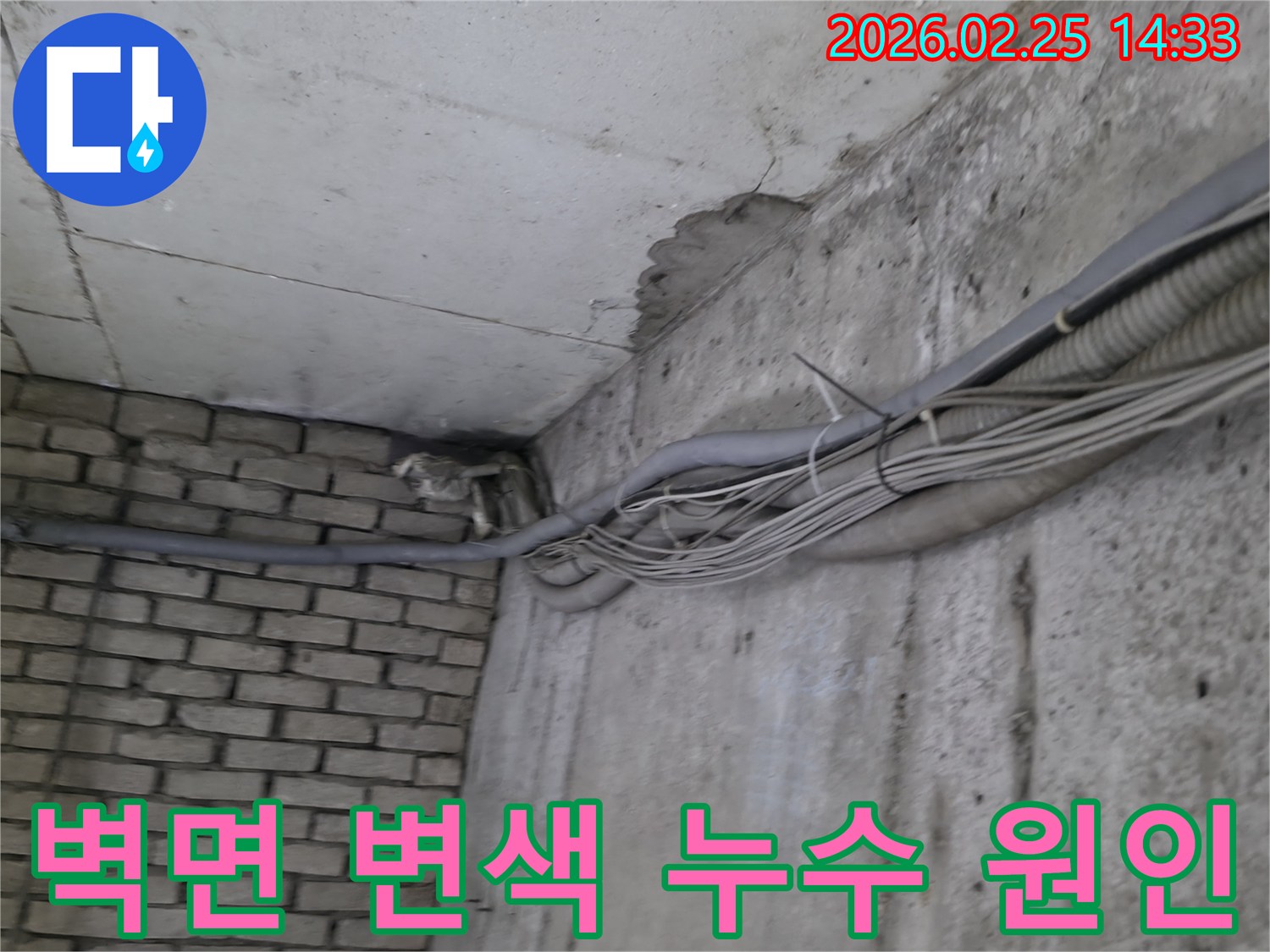 지하 벽면의-콘크리트와-벽돌 벽이 만나는-지점에서-발견된-오랜 누수로 인한-짙은 물자국과-변색 그리고-주변 배관
