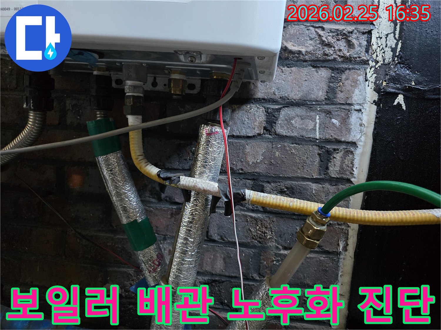 이 이미지는-벽에 설치된-보일러 하단부의-복잡한 배관 연결부와-전선-그리고-은색 단열재로-감싸진-파이프들을-보여주며-누수 원인 중-배관 노후화를-진단하기 위한-점검이-진행되고-있음을-암시합니다.