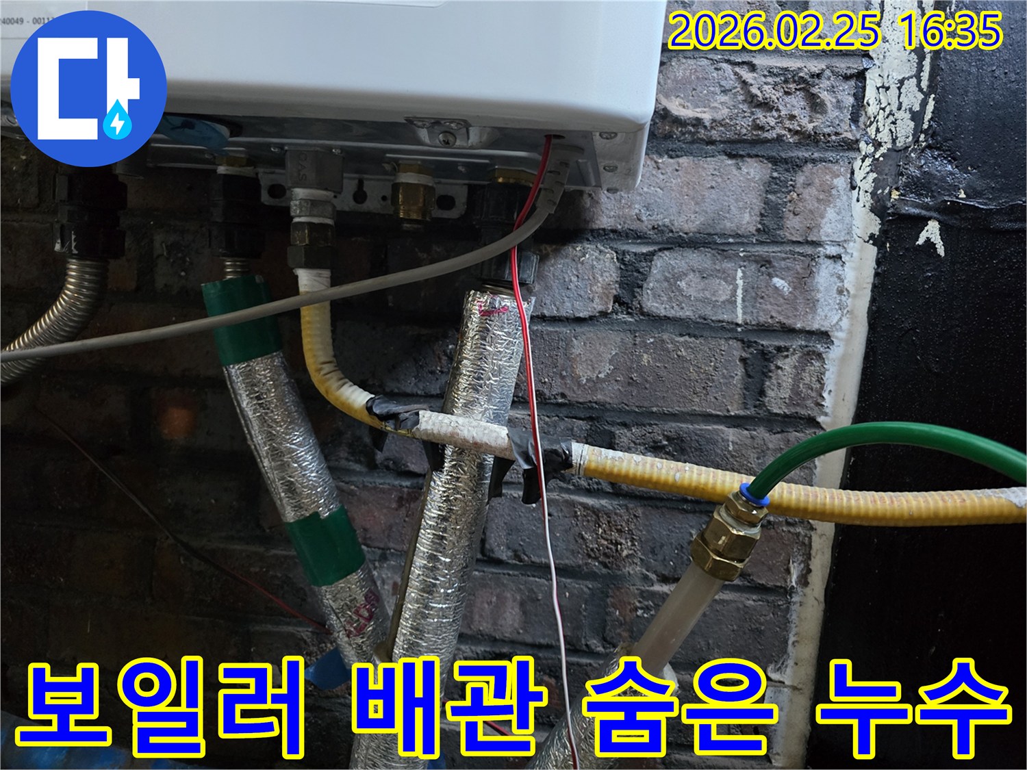이 이미지는-벽에 설치된-보일러 하단부의-복잡한 배관 연결부와-전선-그리고-은색 단열재로-감싸진-파이프들을-보여주며-숨겨진 누수 지점을-찾기 위한-정밀한 점검이-필요함을-암시합니다.