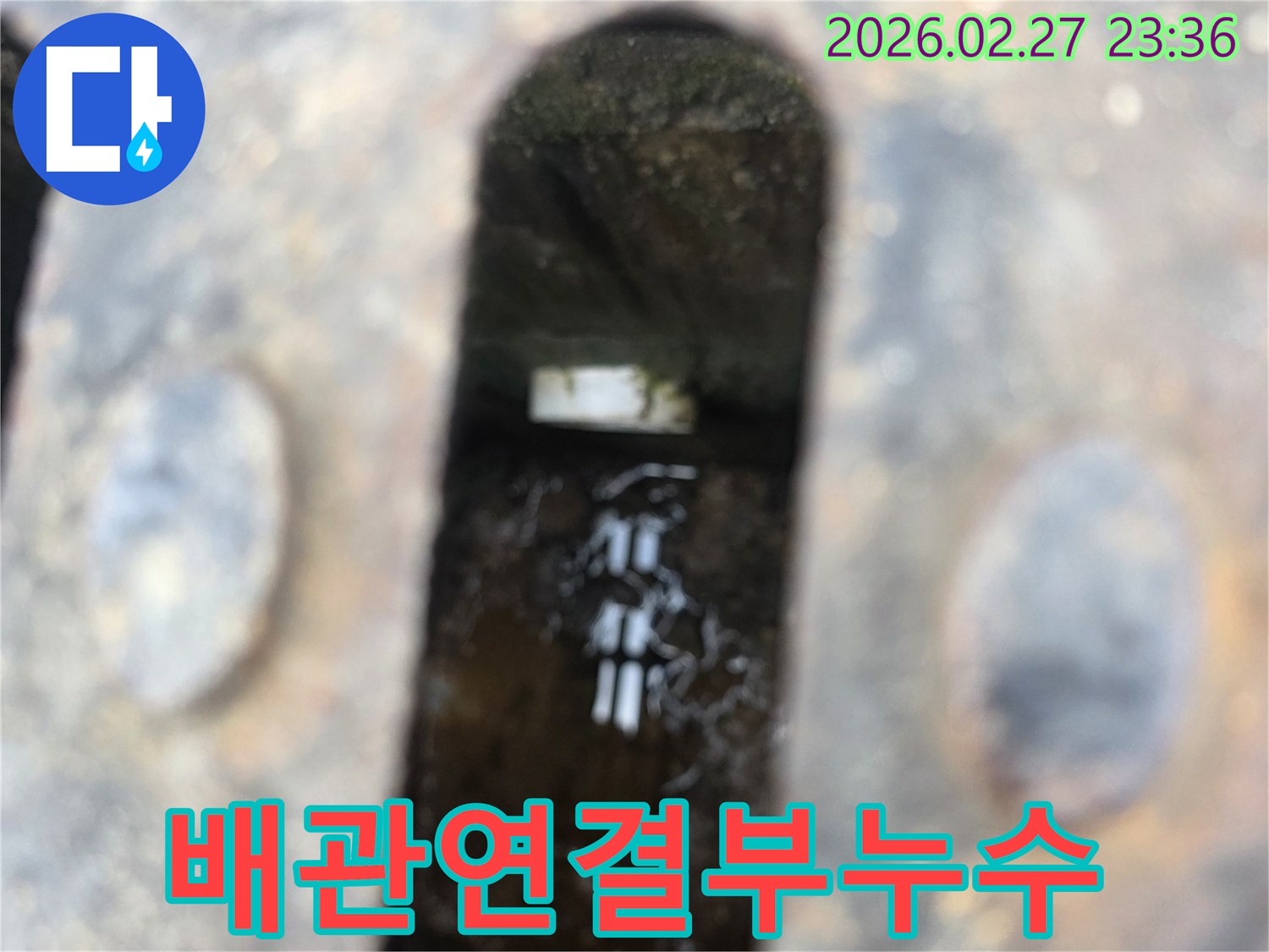 녹슨-철제-배수구-아래-고인-물과-물속에-잠긴-배관-연결부가-보이는-누수-현장