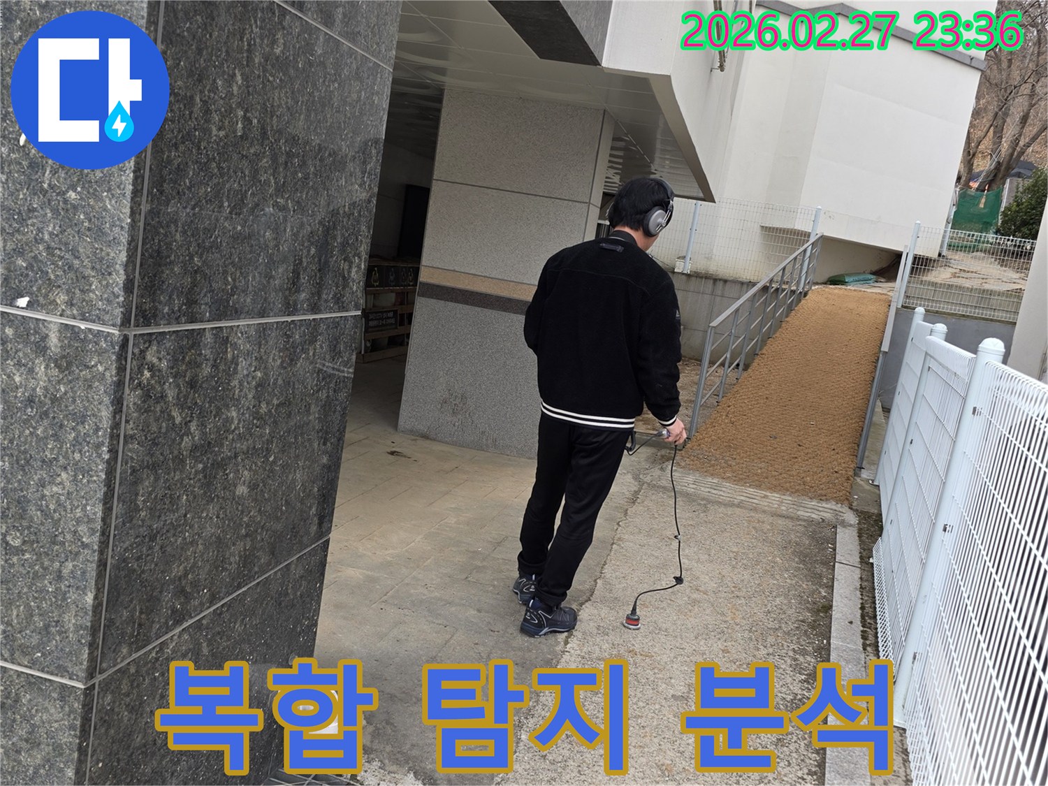 누수 엔지니어가-청음식 탐지 장비로-건물 외부의-누수 지점을 정밀하게 분석하여-복합적인 탐지 과정을 수행하는 모습