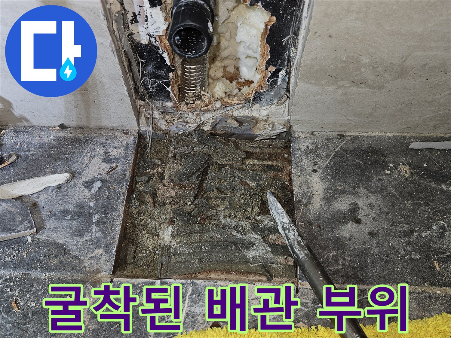 타일 아래 노출된 파손된 수도 배관의 상세 사진