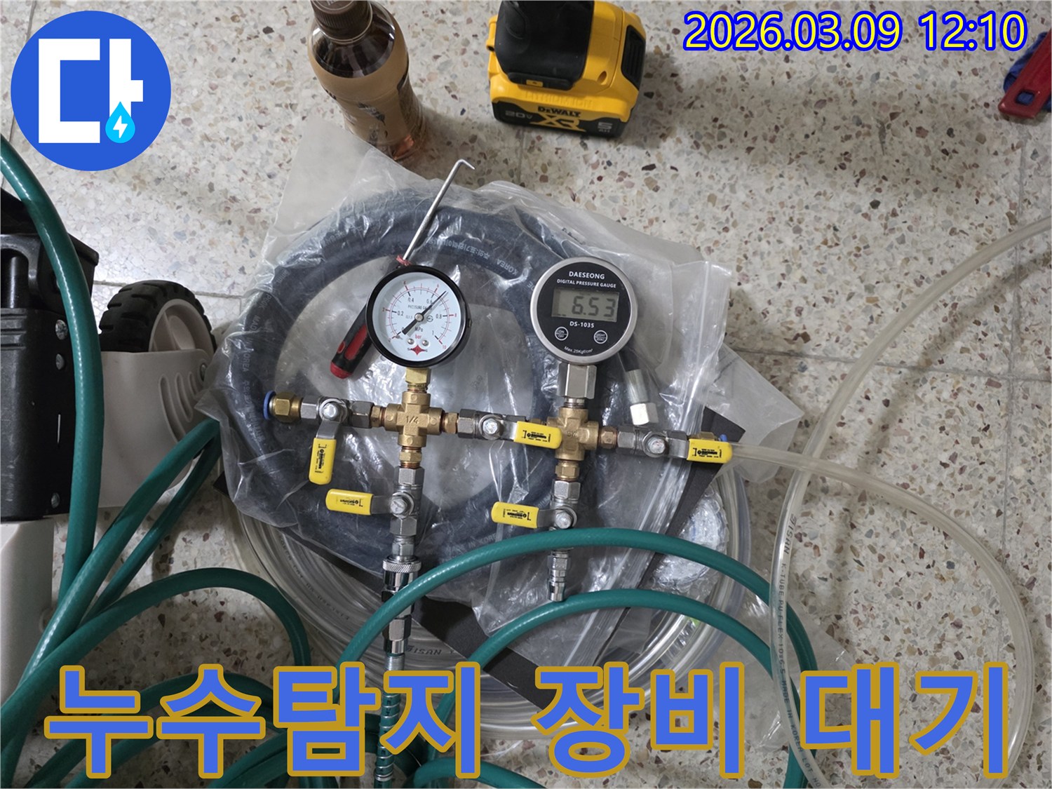 누수 공사를 위한 정밀한 누수탐지 장비들이-압력계-호스-밸브 등과 함께 바닥에 가지런히 놓여 있습니다.