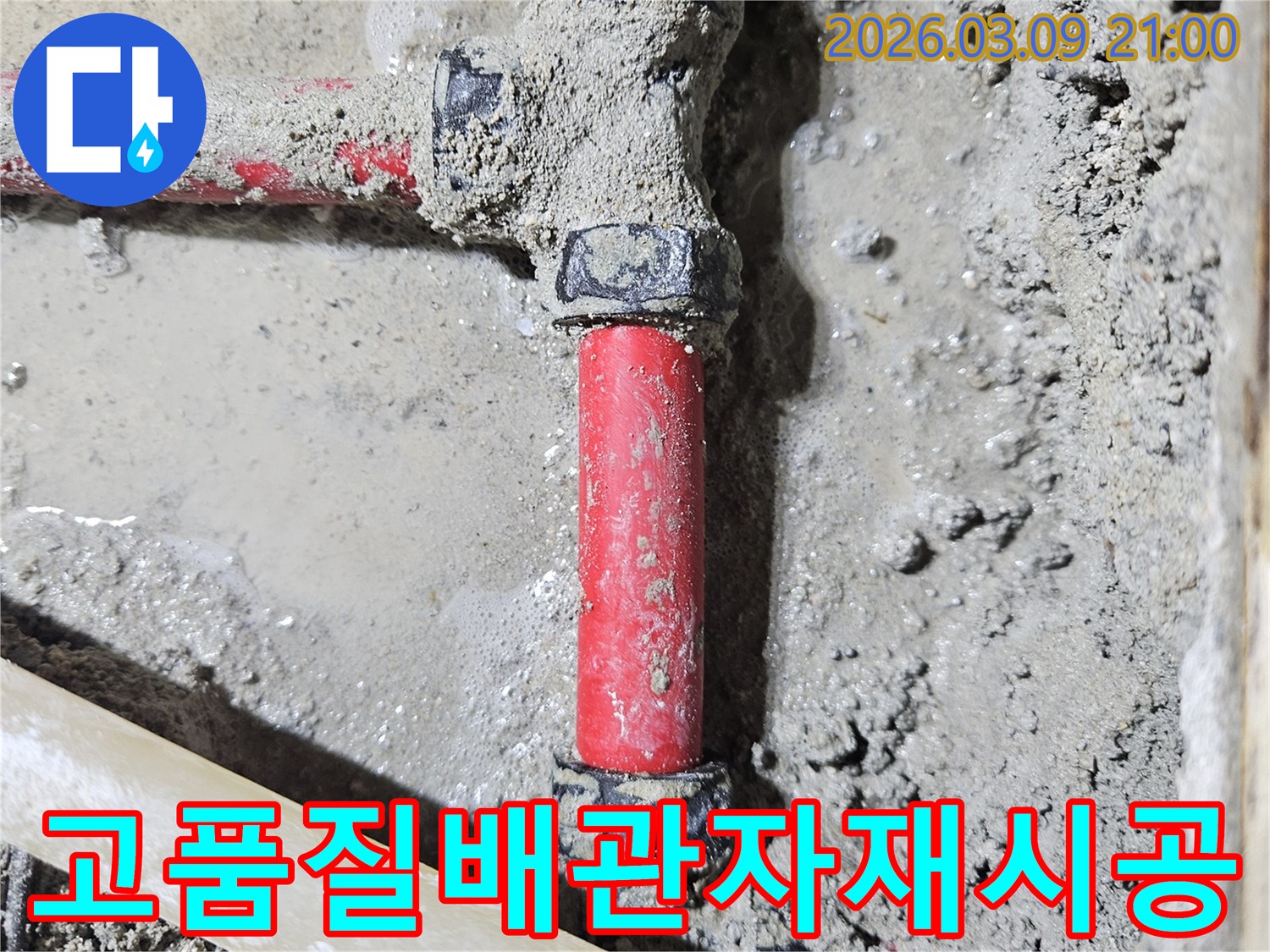 젖은 시멘트 바닥에-매립된 빨간색 배관의-누수 지점을-고품질 자재로-교체하여-안전하게 보수한-모습입니다