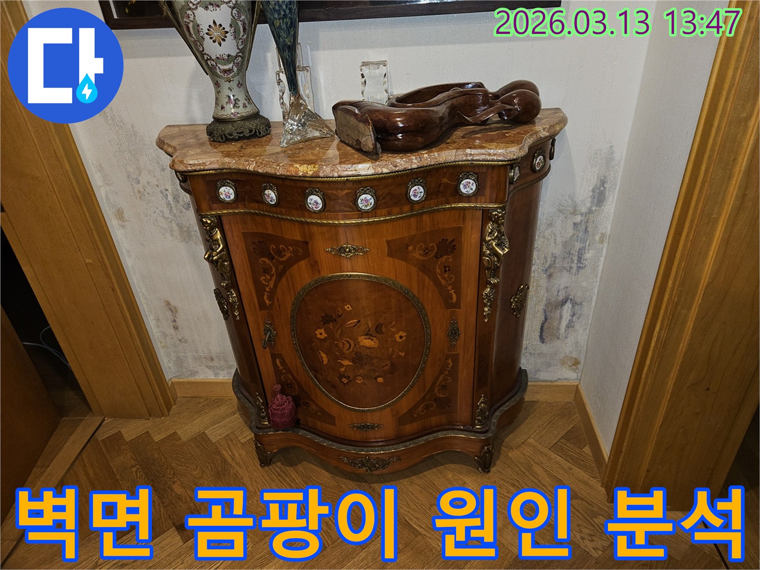 고급스러운 콘솔 가구 뒤-벽에 발생한-누수로 인한-벽지 변색과-곰팡이 흔적을 보여주는 사진