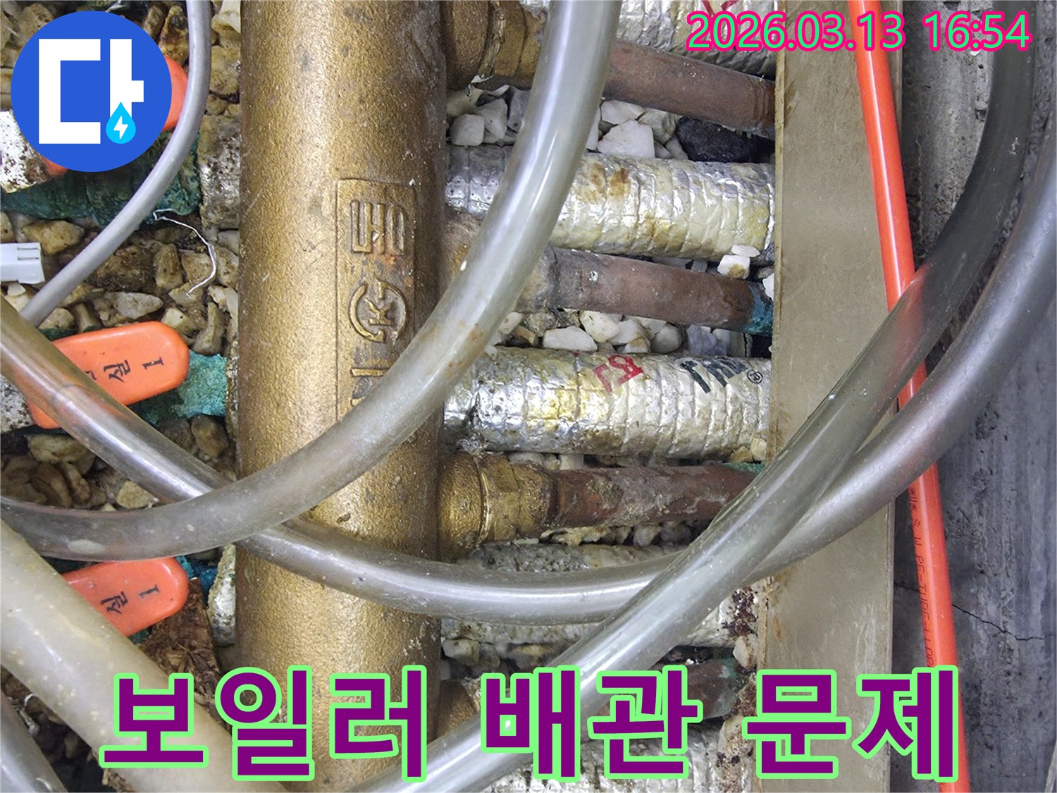 온수 분배기의-부식된 배관과-누수 흔적을-자세히-보여주는-클로즈업 사진입니다.
