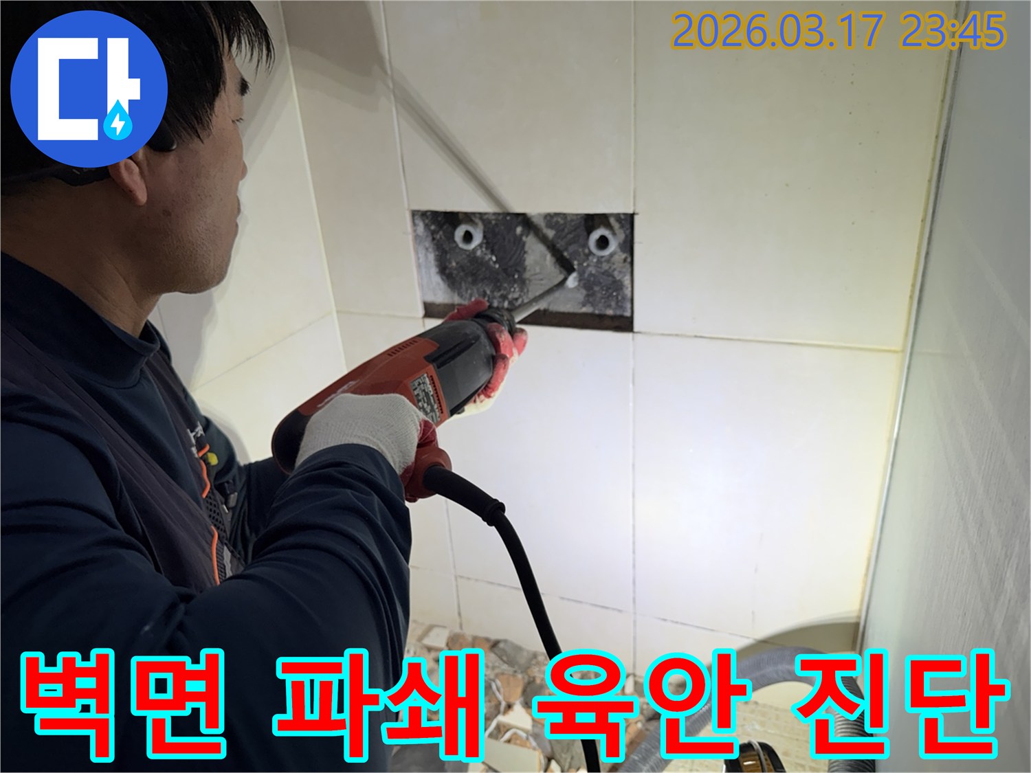 누수 전문가가 벽면 타일을 깨끗하게 파쇄하며-누수 원인인 배관의 문제점을 육안으로 검사하고 진단하는 작업을 진행 중입니다.