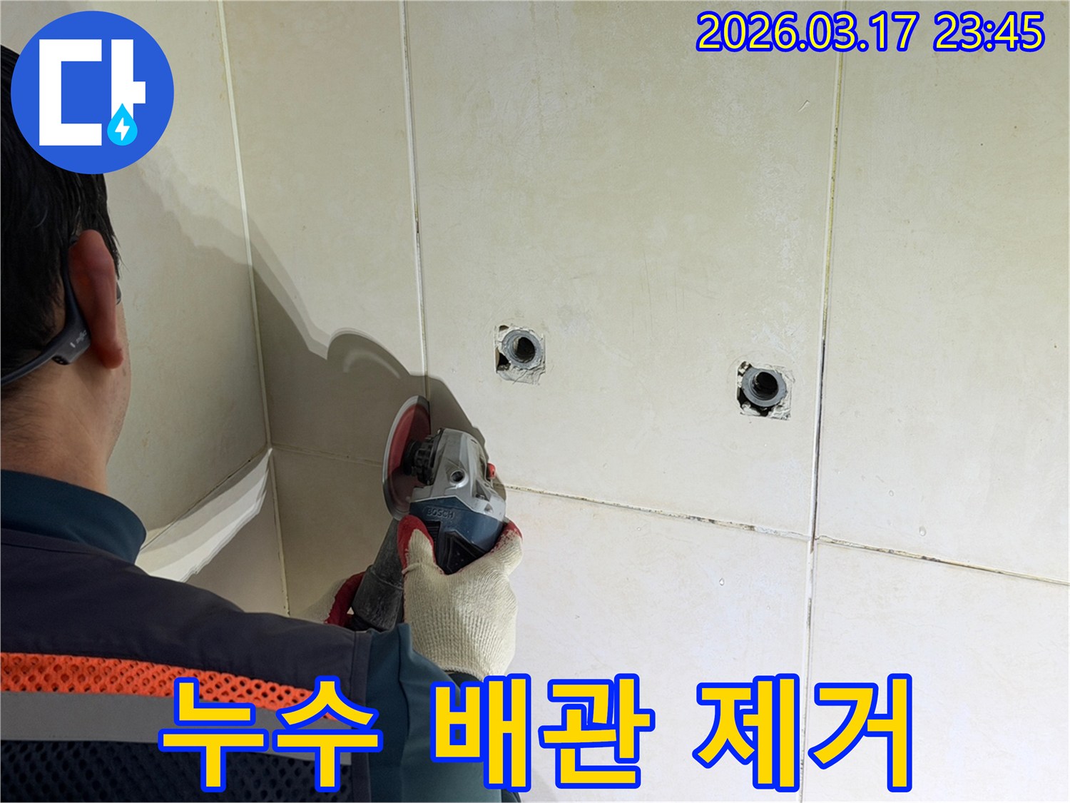누수된 배관을-노출시키기 위해-전문가가-타일 벽면을-그라인더로-조심스럽게-제거하고-있습니다