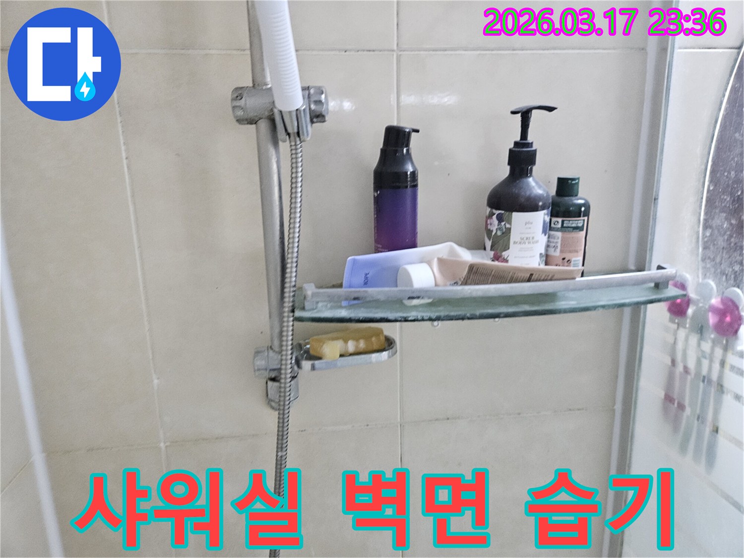 욕실 샤워기 옆-유리 선반 아래로-물방울이 맺혀-물고임 현상을 보여주는-누수 현장 사진입니다