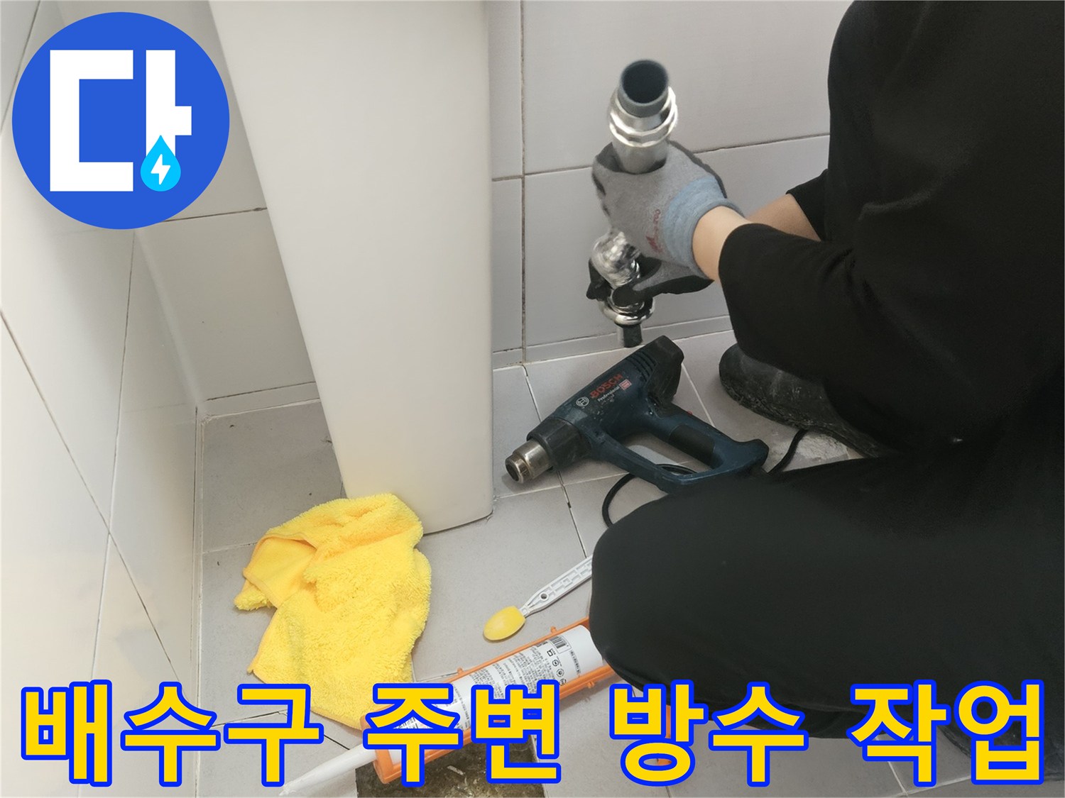 화장실 배수구 유가 주변에 실란트와 전동 드릴을 이용한 방수 보강 작업 중인 모습
