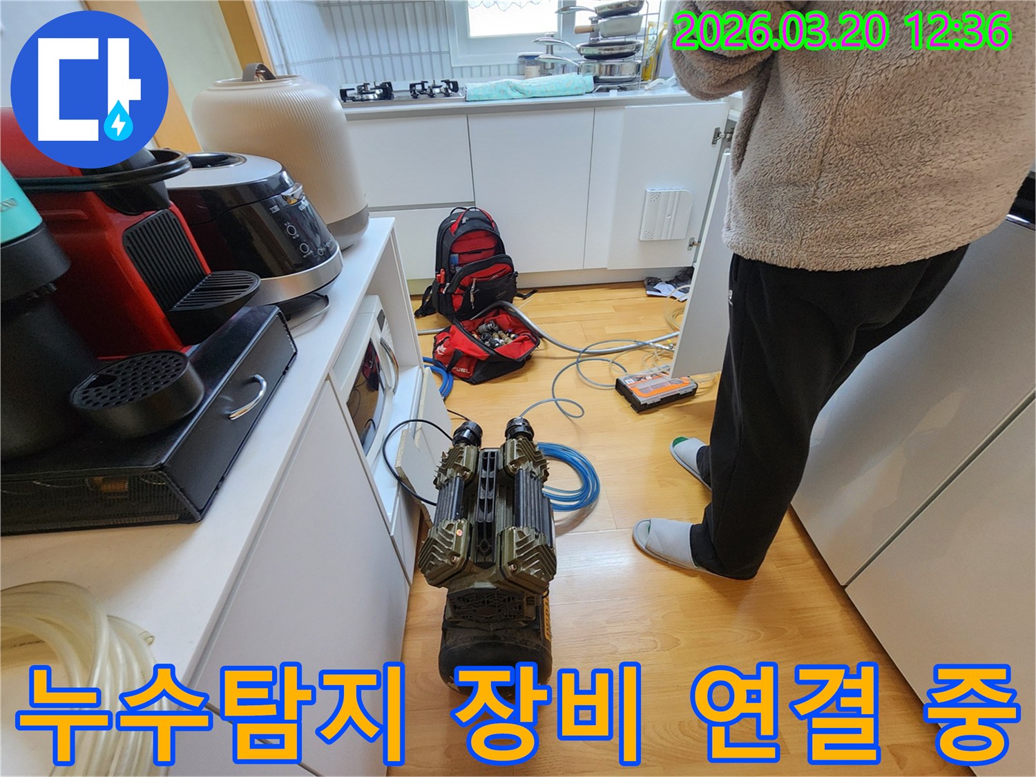 누수 엔지니어가-주방에서 발생한 누수를-탐지하기 위해-전문 장비를-연결하고 있는 모습