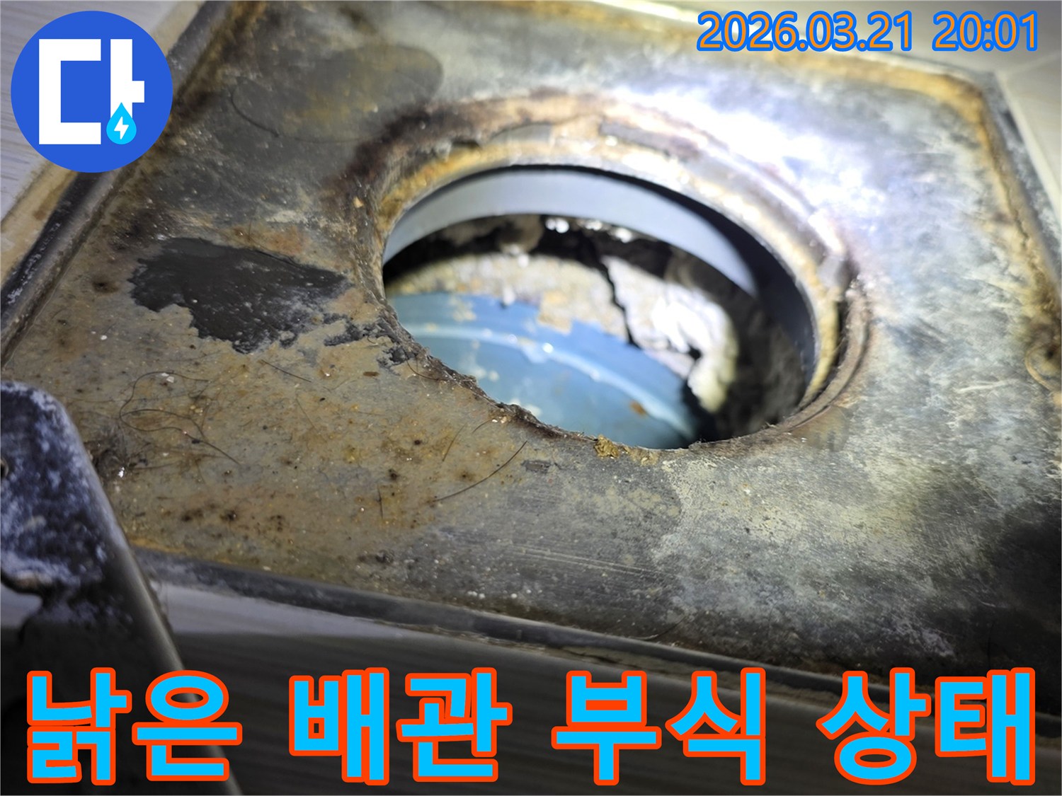 부식으로 인해-손상된 배관 입구와-그 주변의-녹슨 금속 표면을-확대하여 보여주는 사진입니다.