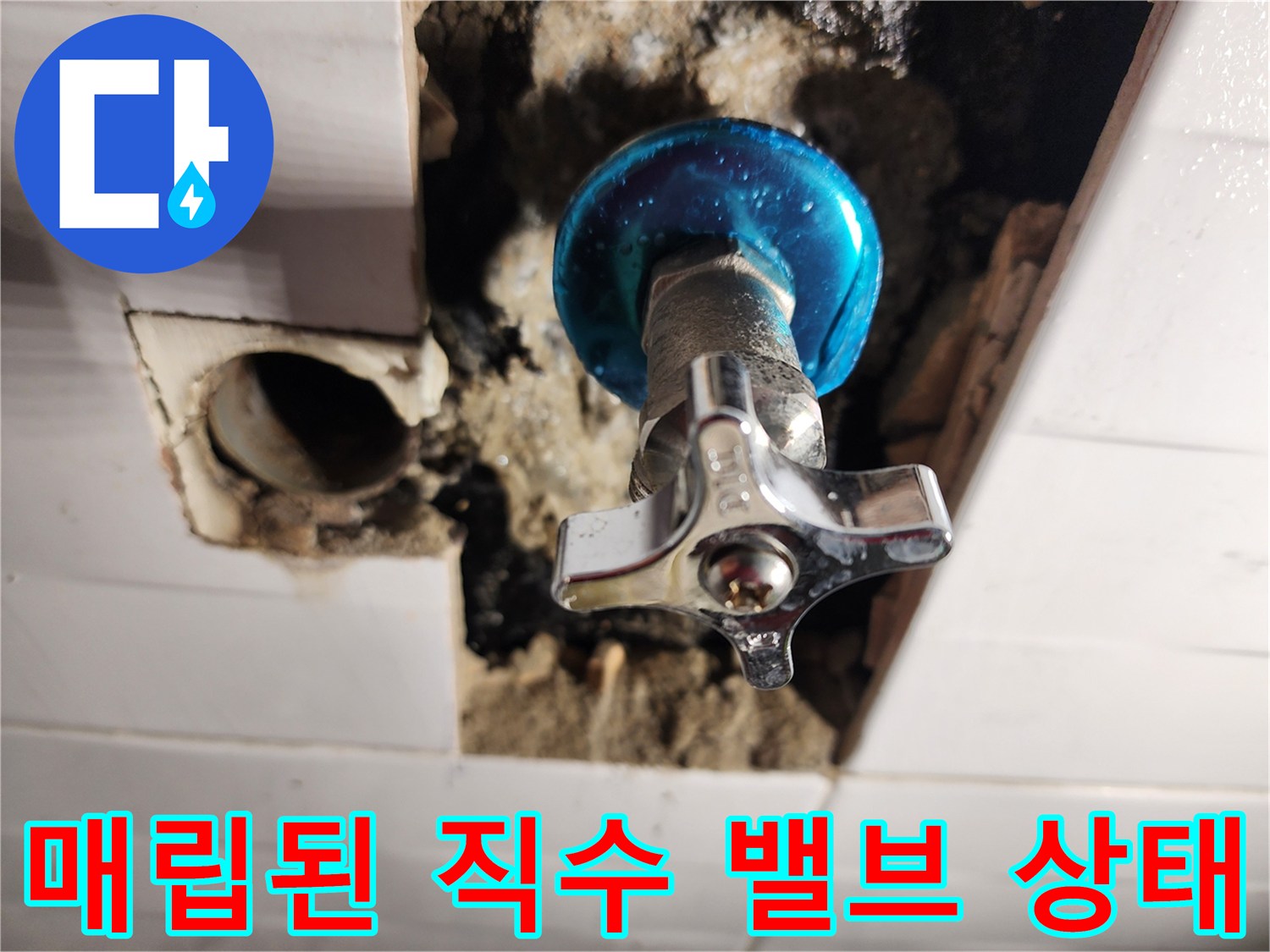벽면 타일 아래-노출된 파란색 수도 밸브와 배관 연결부
