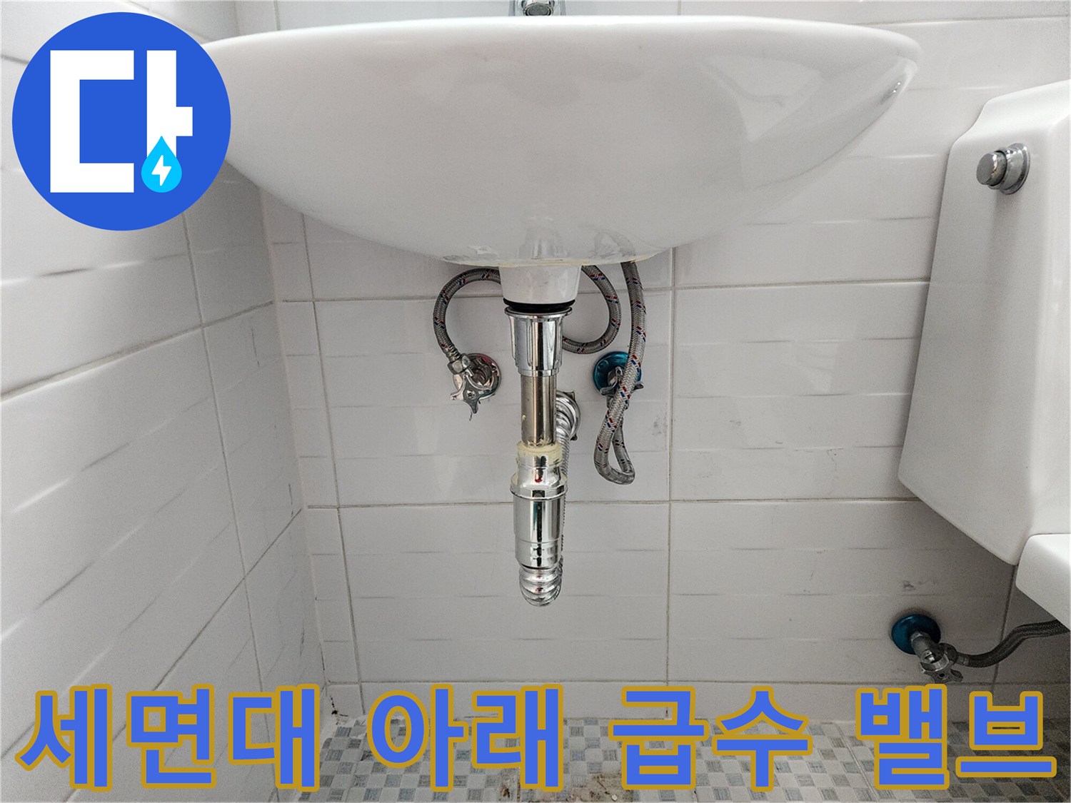 세면대 하단 벽면에 설치된 은색 앵글 밸브와 연결 호스 모습