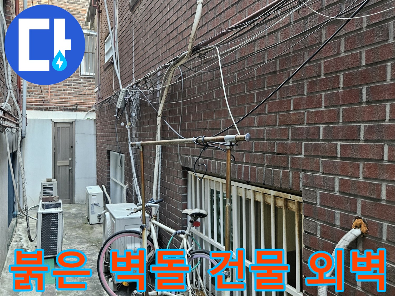 적벽돌 건물의 외부-노출된 다양한 배관 및 전선 시설물
