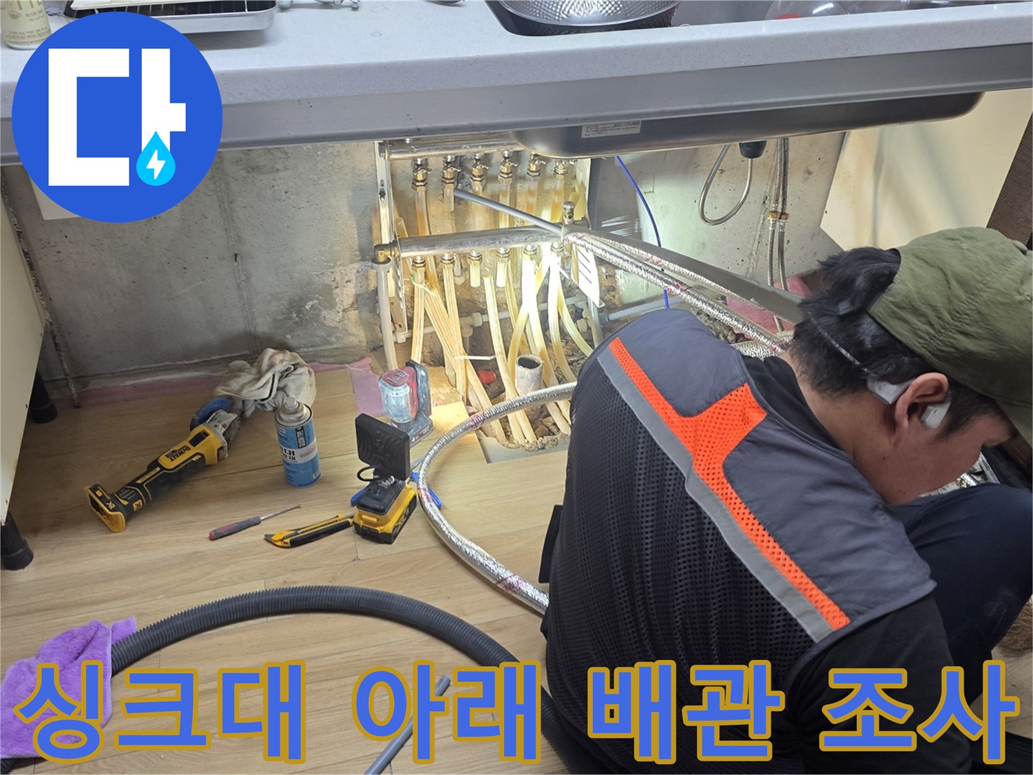 싱크대 하부 공간에서 누수 지점을 찾는 엔지니어의 모습