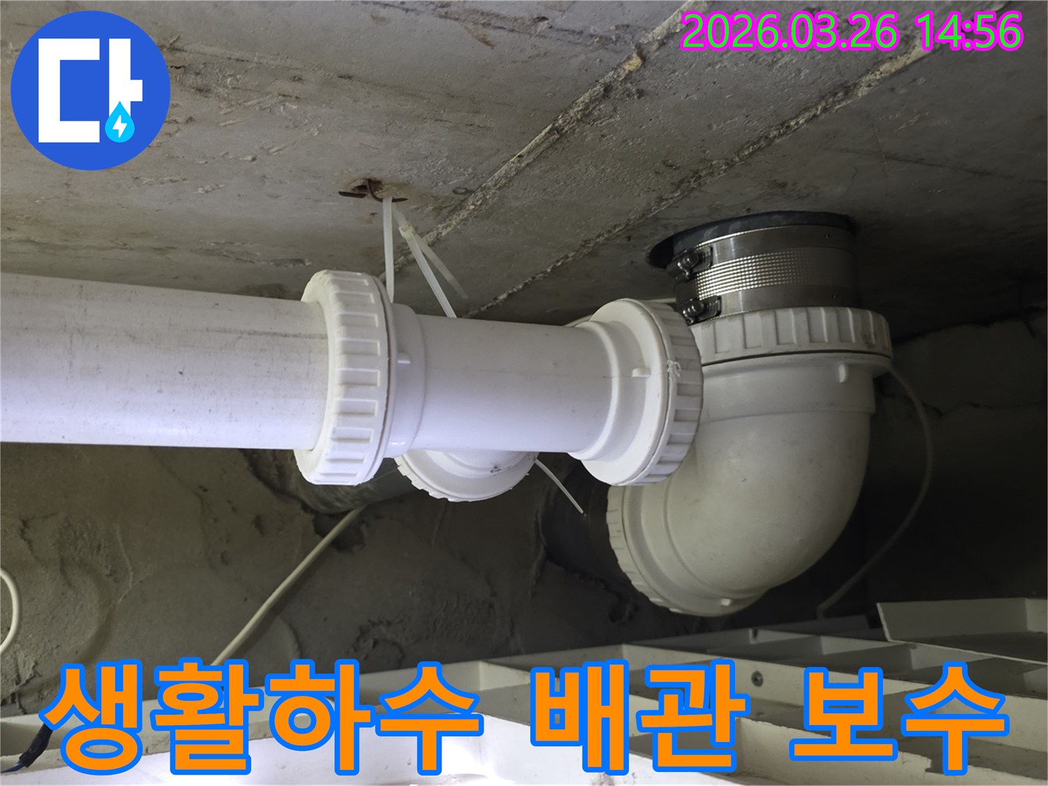 콘크리트 천장 아래에-설치된 생활하수 배관의 연결 부위를-정밀하게 진단하고-보수하는 작업 현장의 모습입니다.
